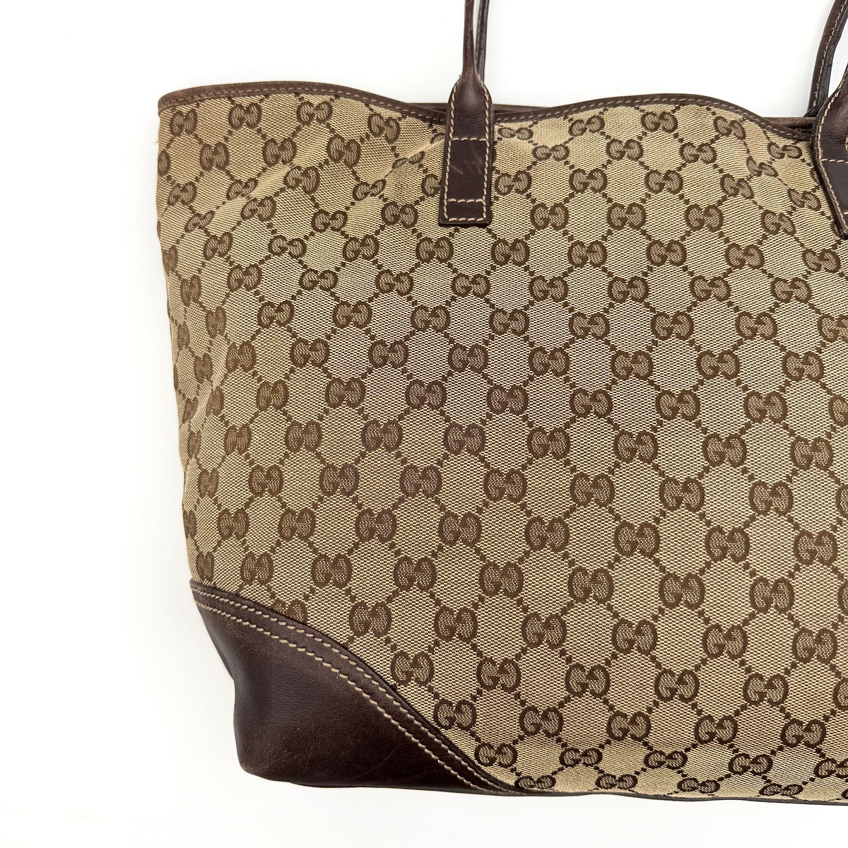 Gucci GG Monogram New Britt Tote Bag in beige and brown canvas with leather trim and gold-tone logo, presented against a white backdrop.