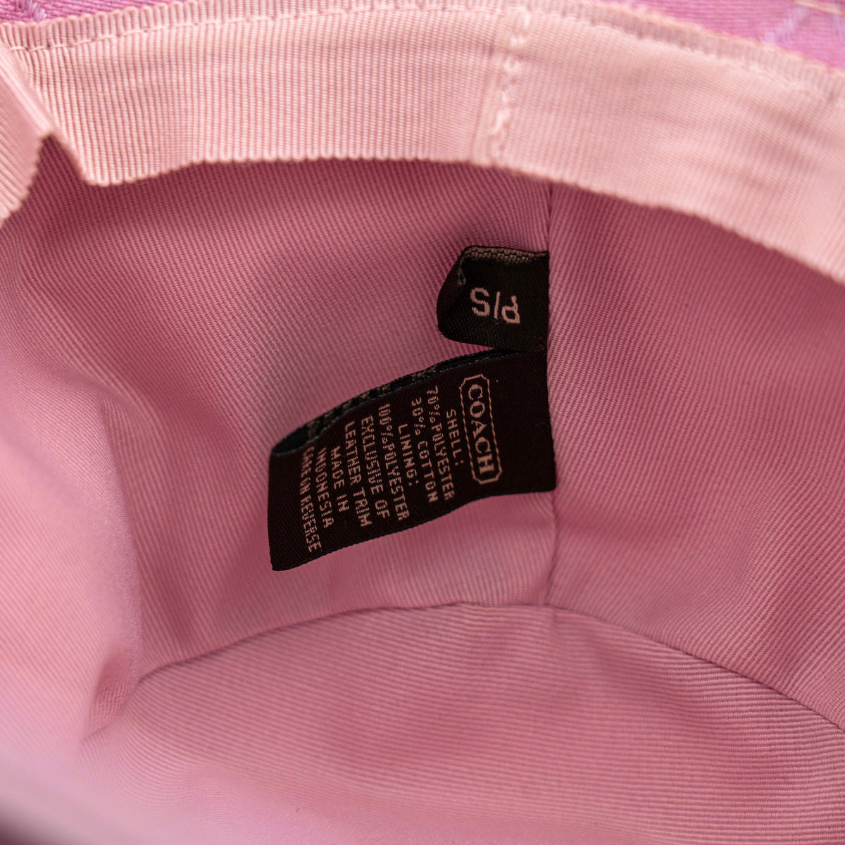 Coach pink jacquard bucket hat with taupe suede-effect band, shown against a neutral background.
