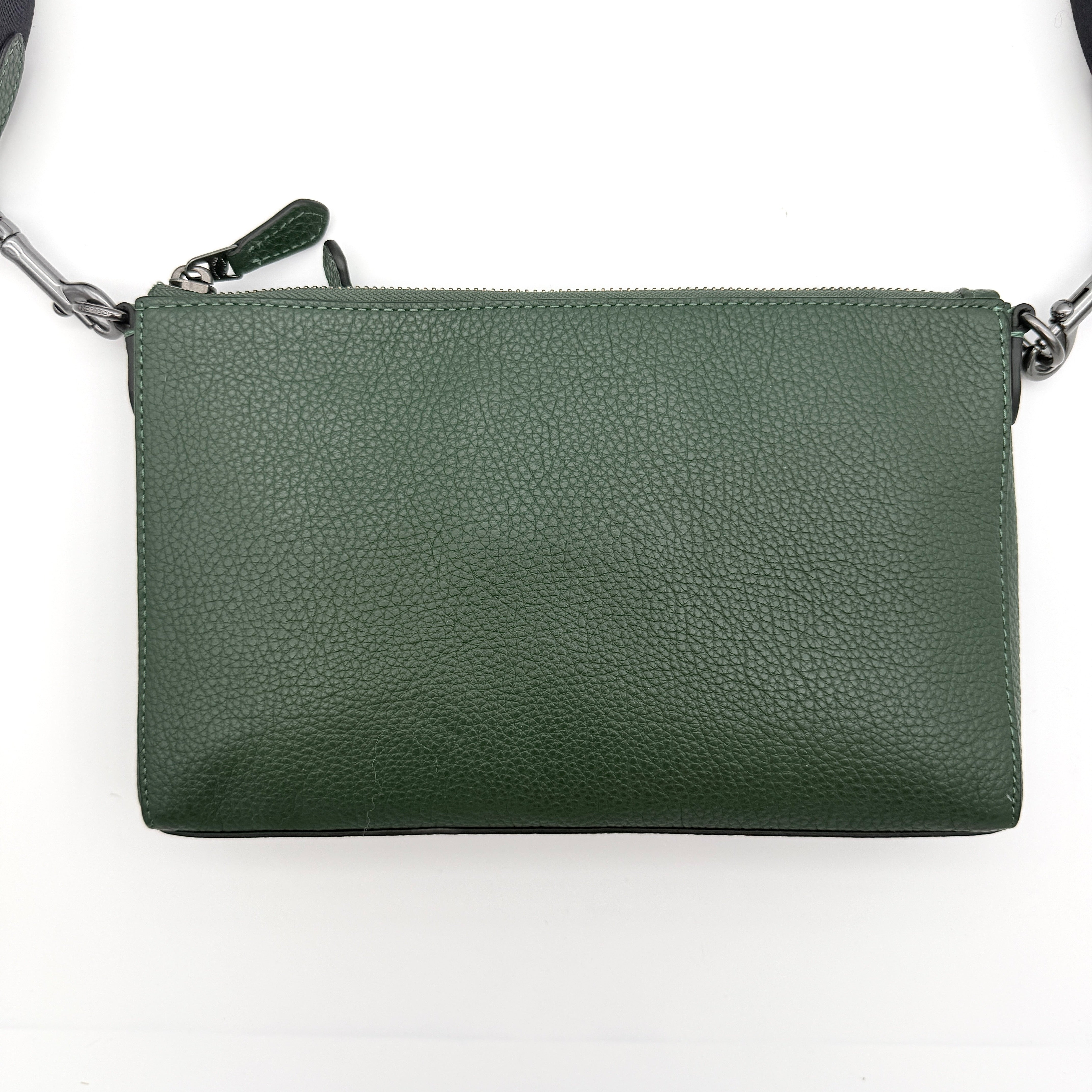 Coach Holden Crossbody bag in dark green pebbled leather with adjustable black webbing strap, displayed against a white background.