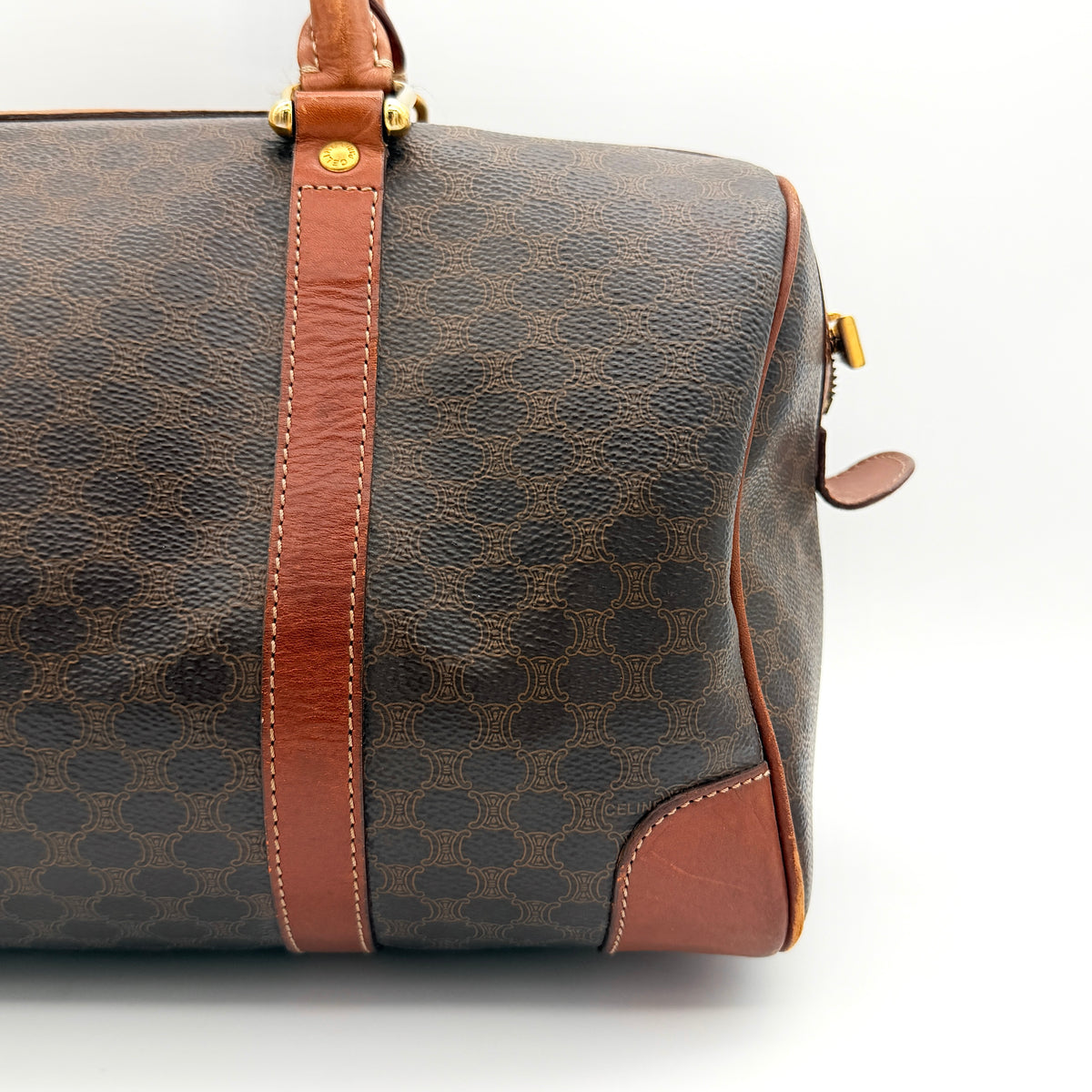 Celine Macadam Triomphe Boston Bag in brown coated canvas with tan leather and gold-tone hardware, shown against a white background.