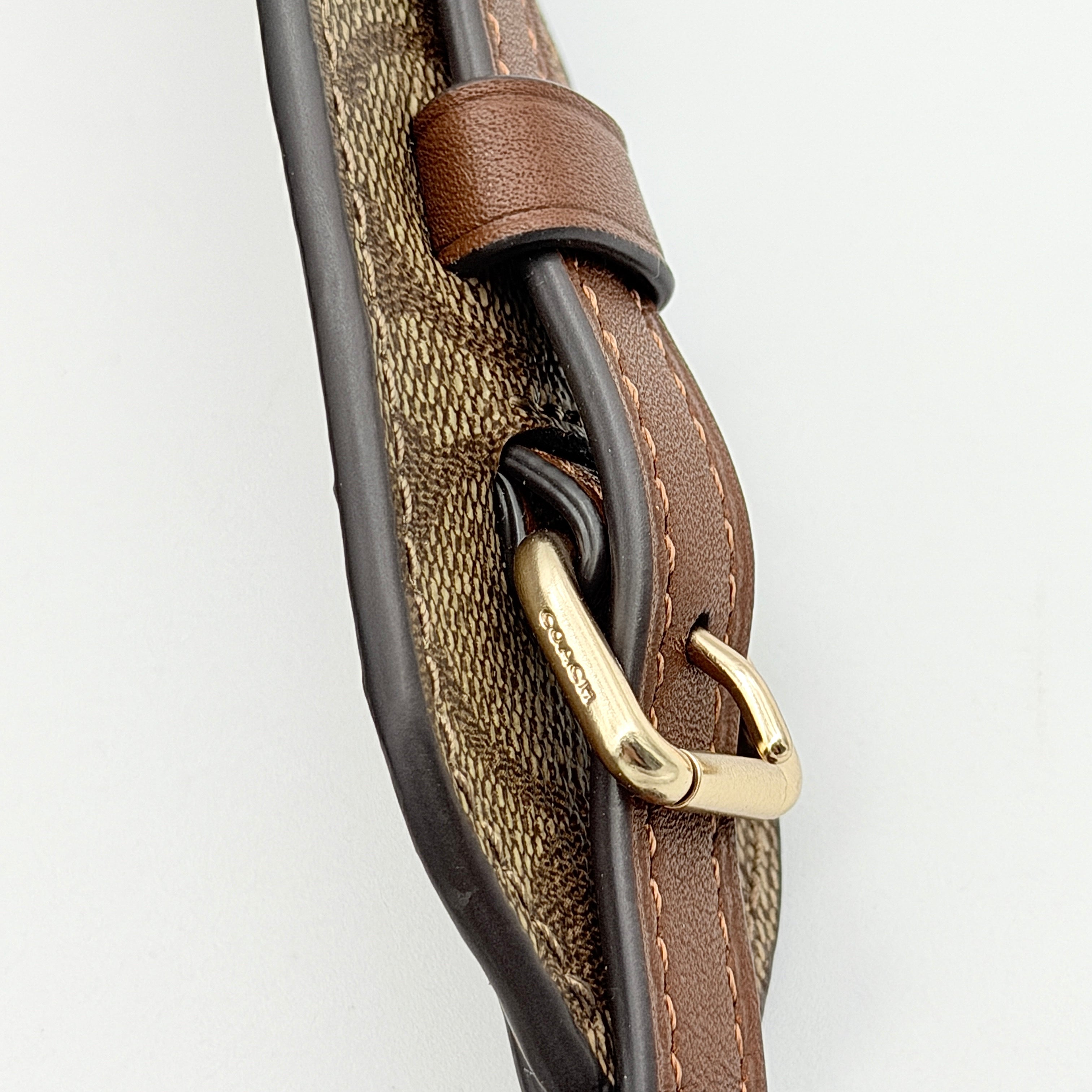 Coach Signature Canvas strap in brown with gold-tone hardware and monogram pattern, shown with Coach dust bag.