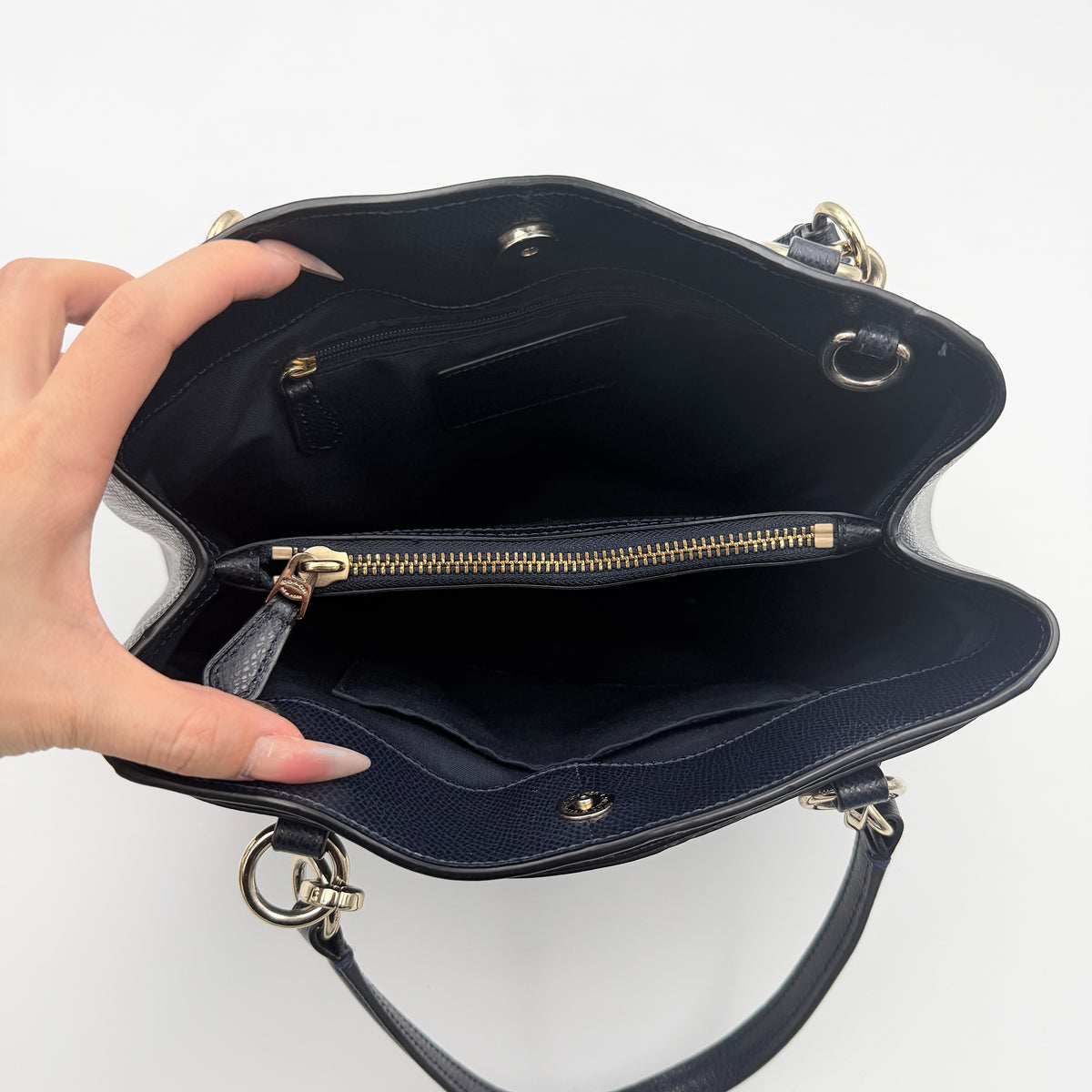 Coach Minetta Satchel in navy blue grained leather with dual handles and detachable shoulder strap displayed on a white background.