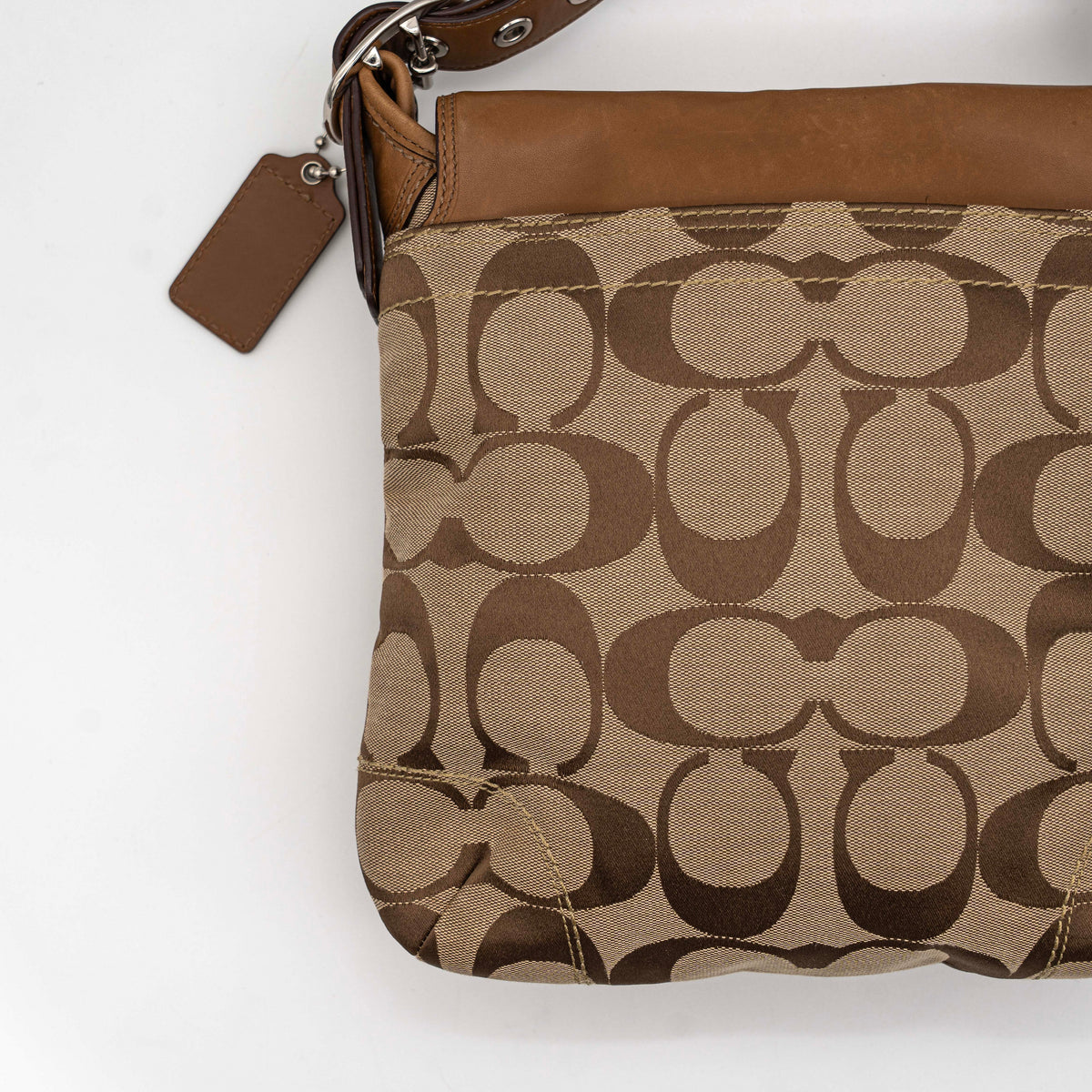Coach 2Way Signature Soho Buckle Flap Shoulder Bag in beige and tan with silver buckle and adjustable leather strap, shown on a white background.