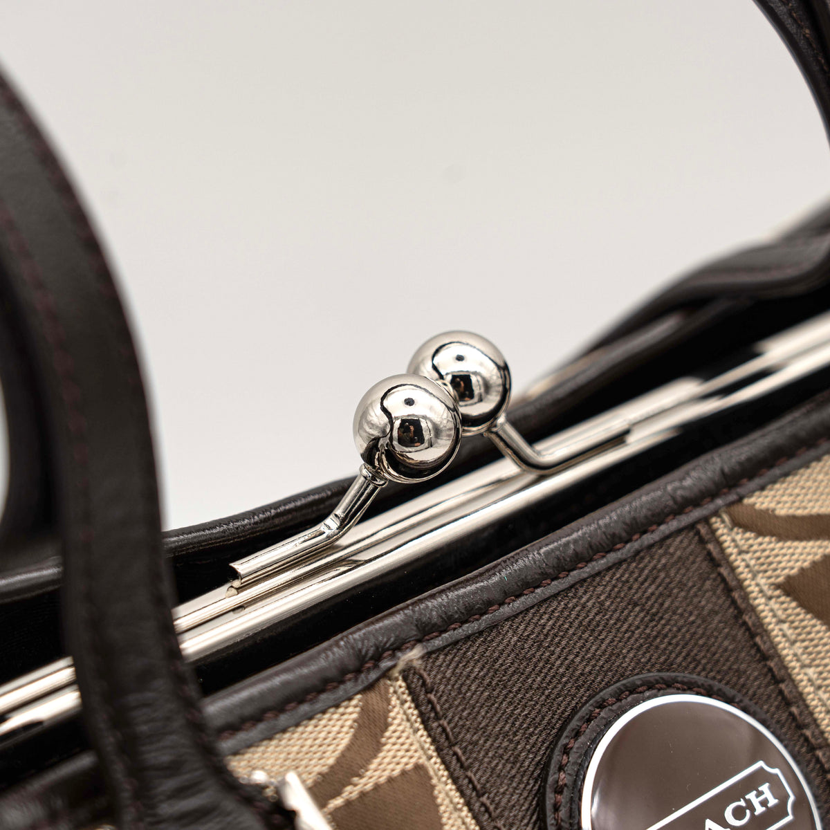 Coach Signature Stripe Frame Kisslock Shoulder Bag in beige and brown canvas with leather trim and signature monogram pattern.
