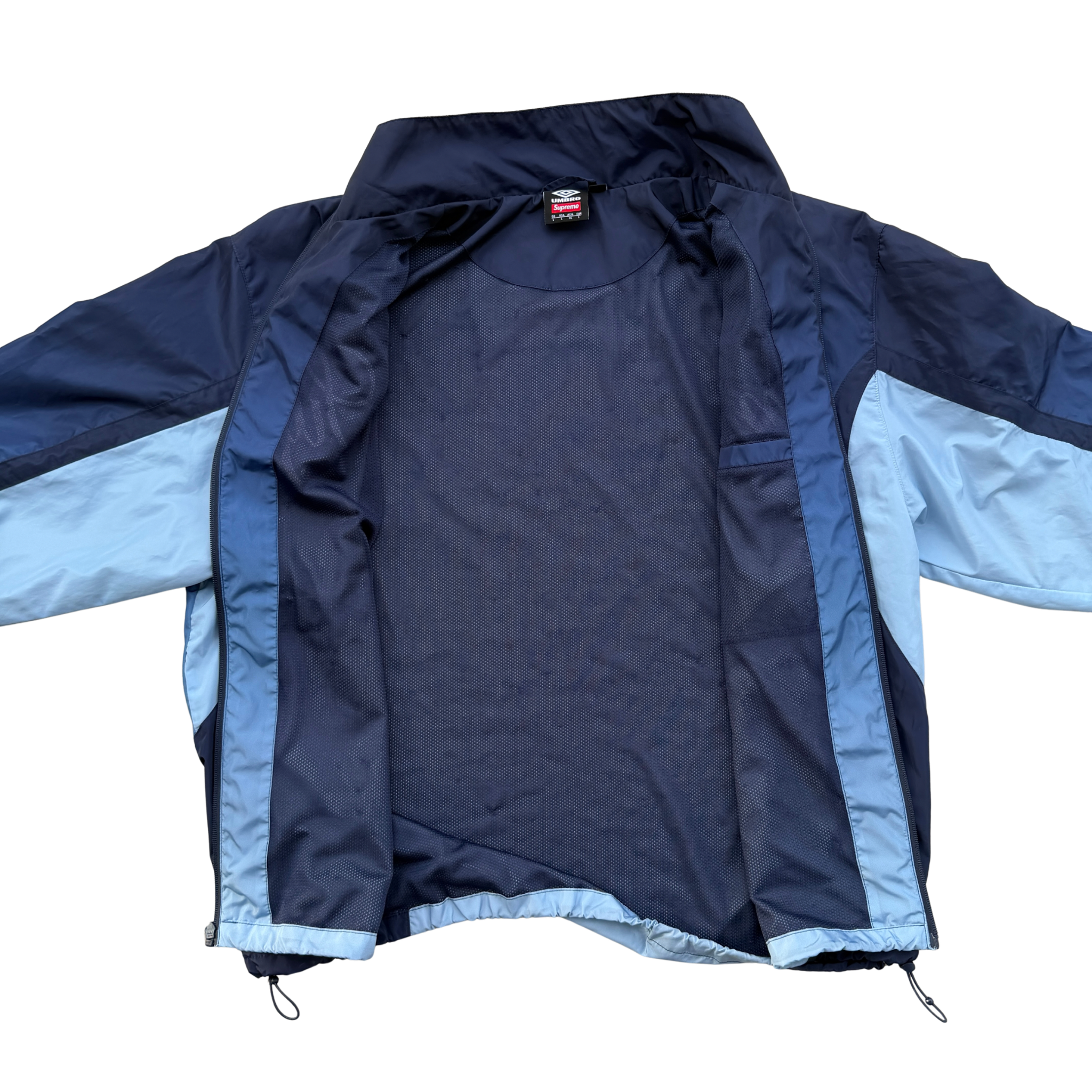 Supreme x Umbro blue gradient track jacket with white Supreme Champions lettering and crest, shown zipped with elastic cuffs and hem.