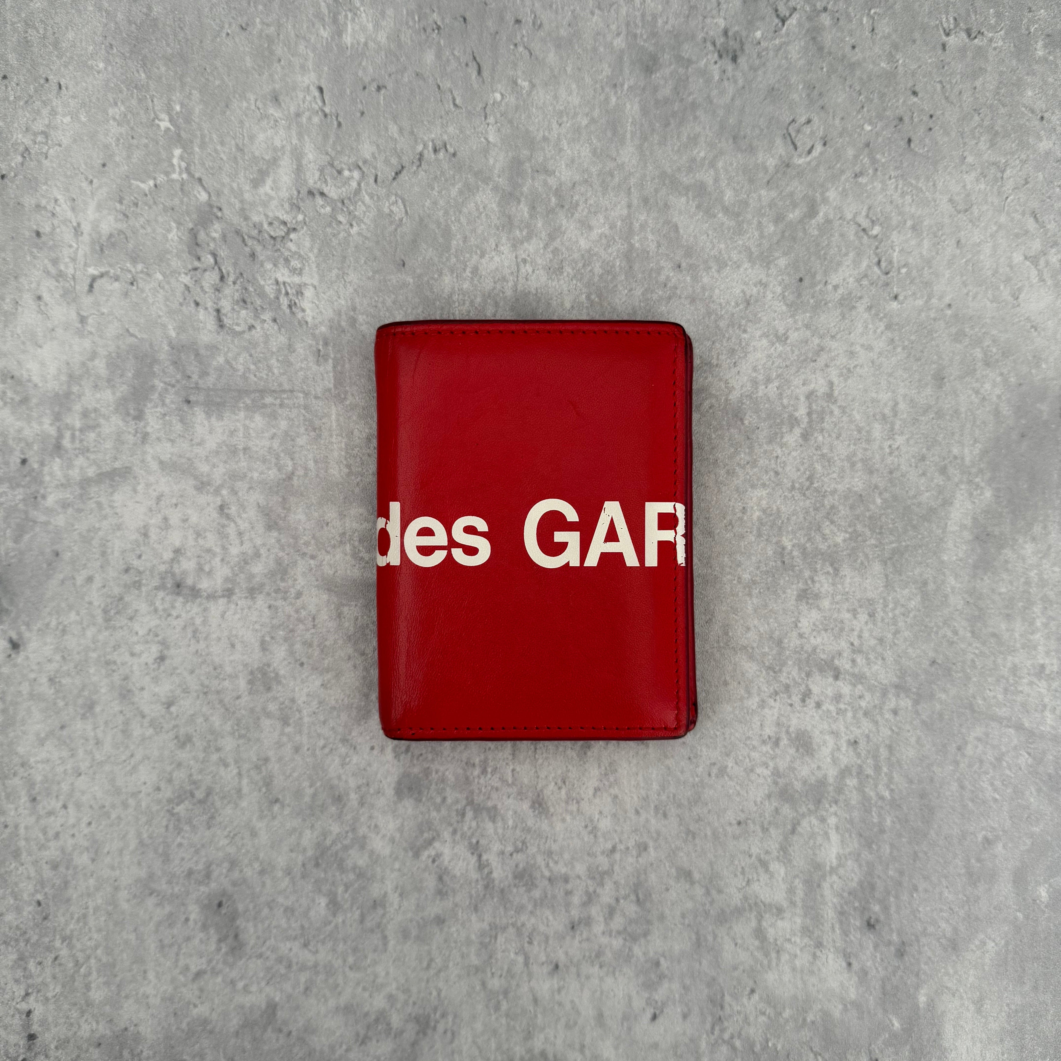 COMME des GARÇONS Huge Logo Red Leather Wallet with oversized white print and multiple card slots in a bi-fold design.