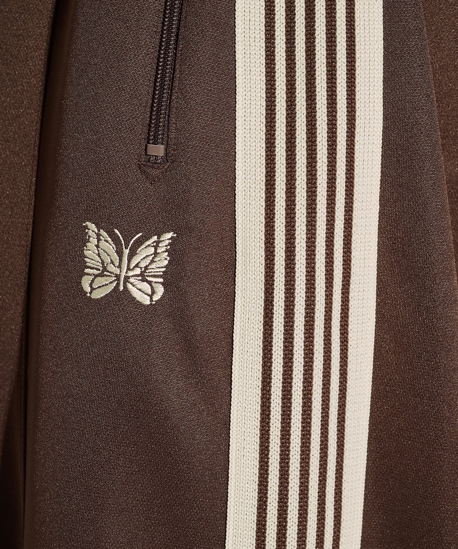 Needles H.D. Track Pant in brown with cream stripes and butterfly embroidery, shown in a side view that highlights the wide leg fit.