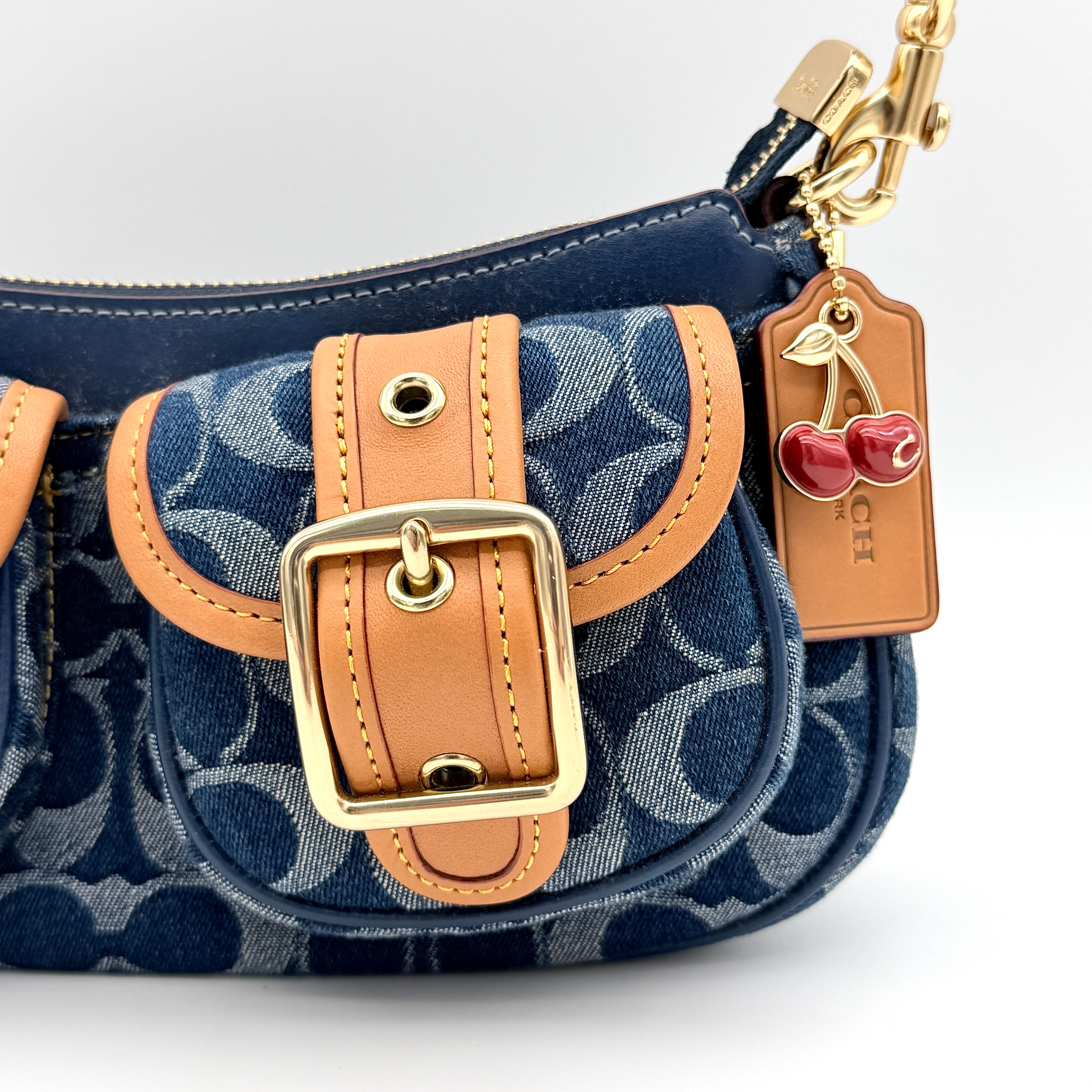 Coach Signature Ashton shoulder bag in blue denim and tan leather with gold hardware, shown with removable strap and dust bag.