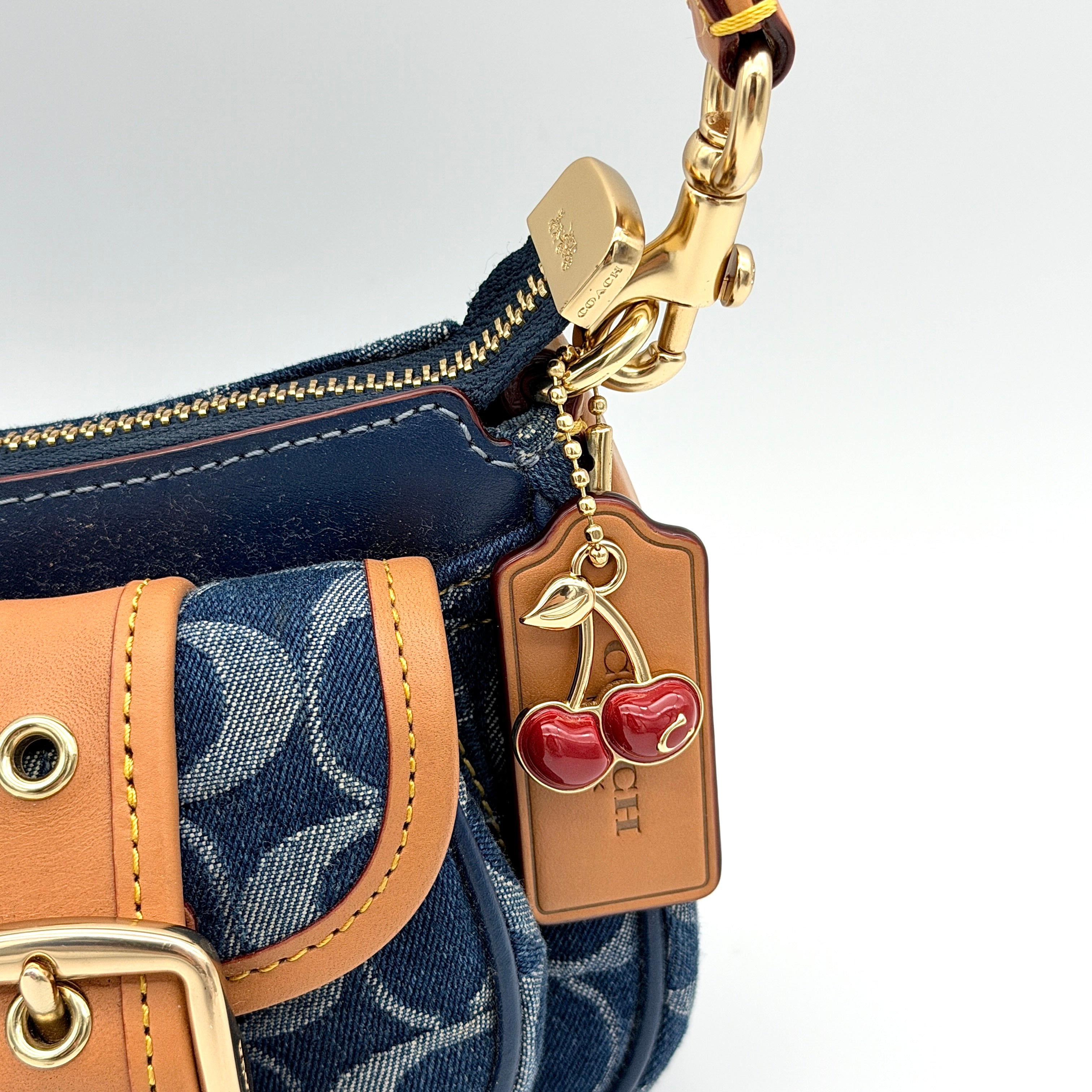 Coach Signature Ashton shoulder bag in blue denim and tan leather with gold hardware, shown with removable strap and dust bag.