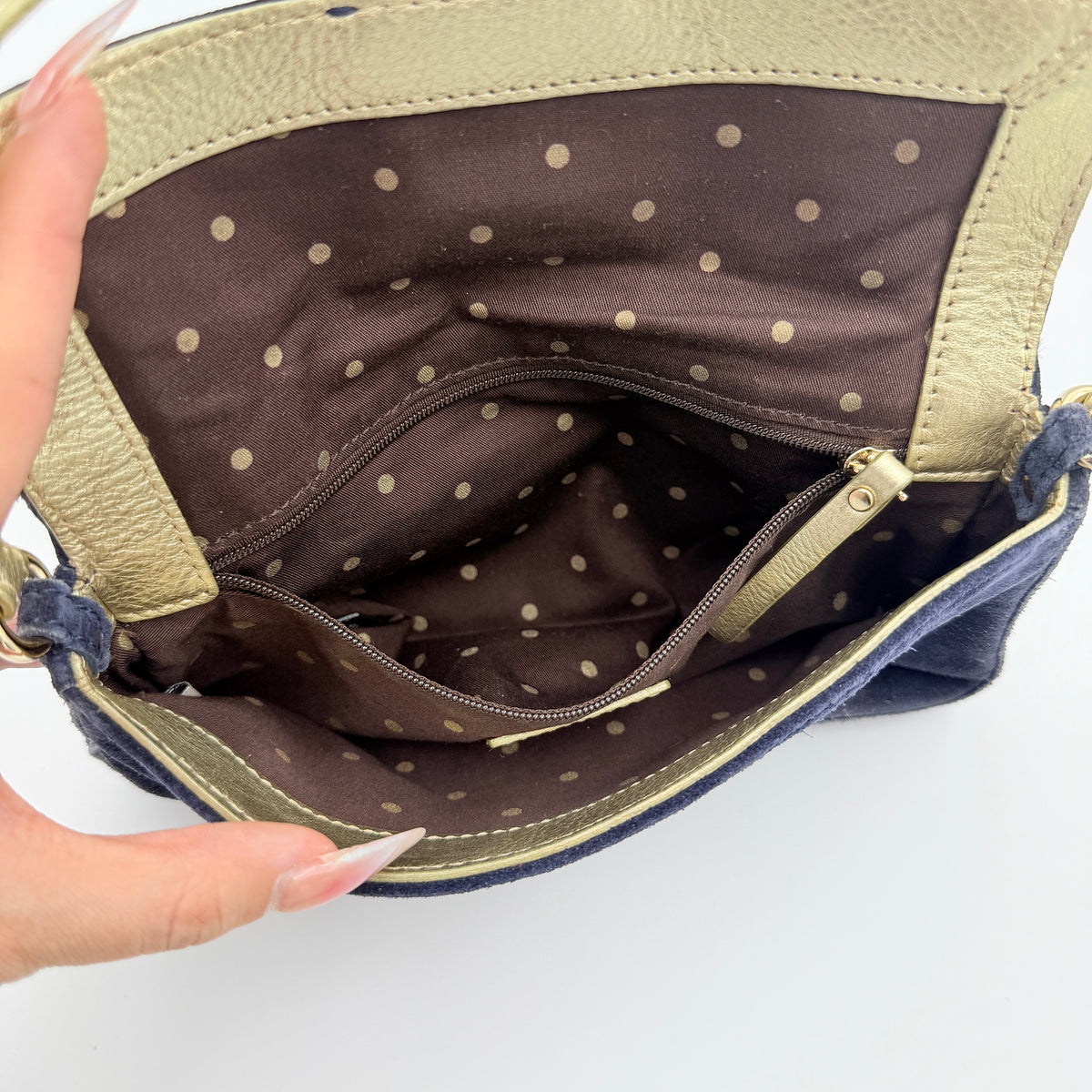 Navy blue suede Kate Spade baguette bag with floral gold hardware and gold-tone shoulder strap.