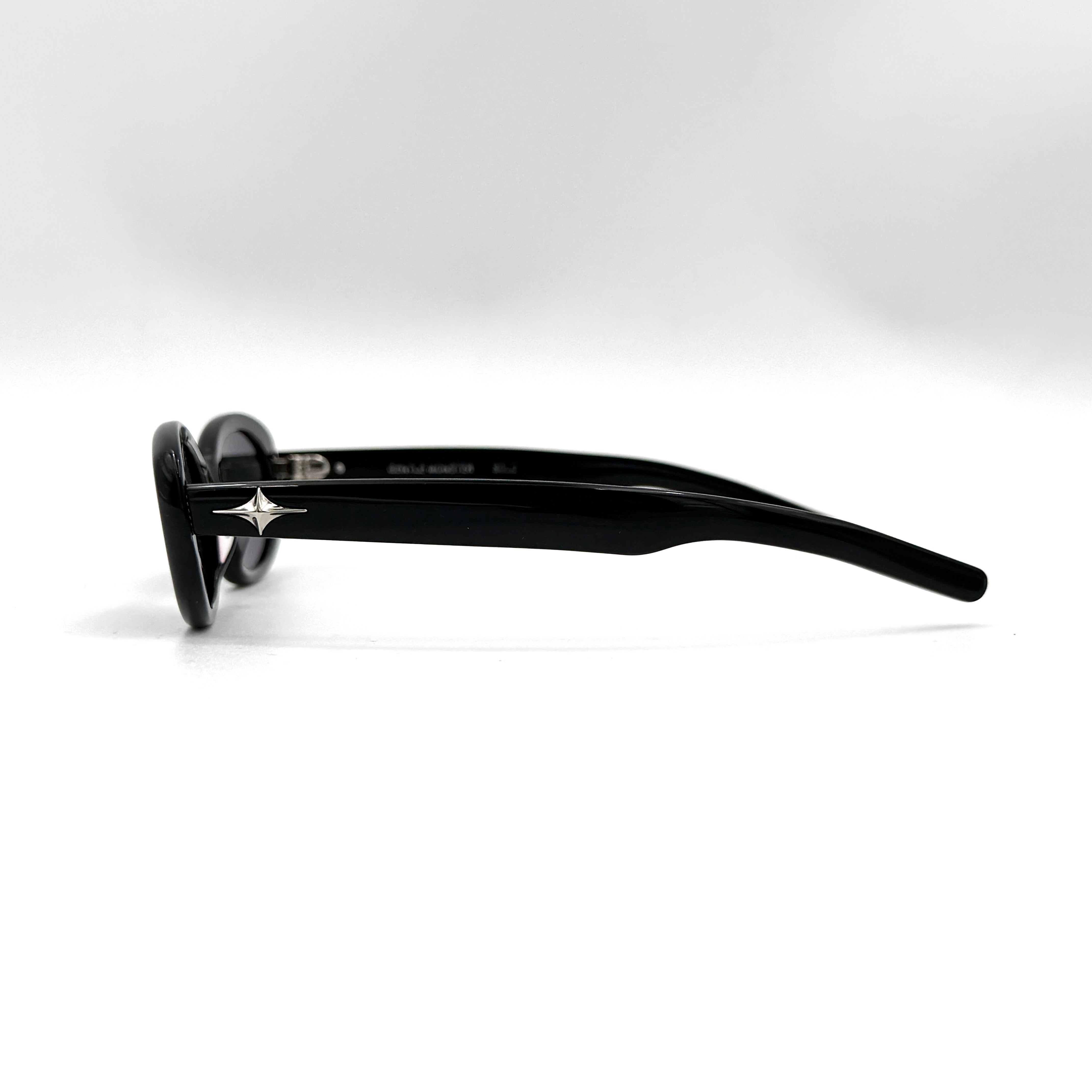 Gentle Monster Bandoneon.S sunglasses in black acetate with dark oval lenses and silver star accents shown from the side.
