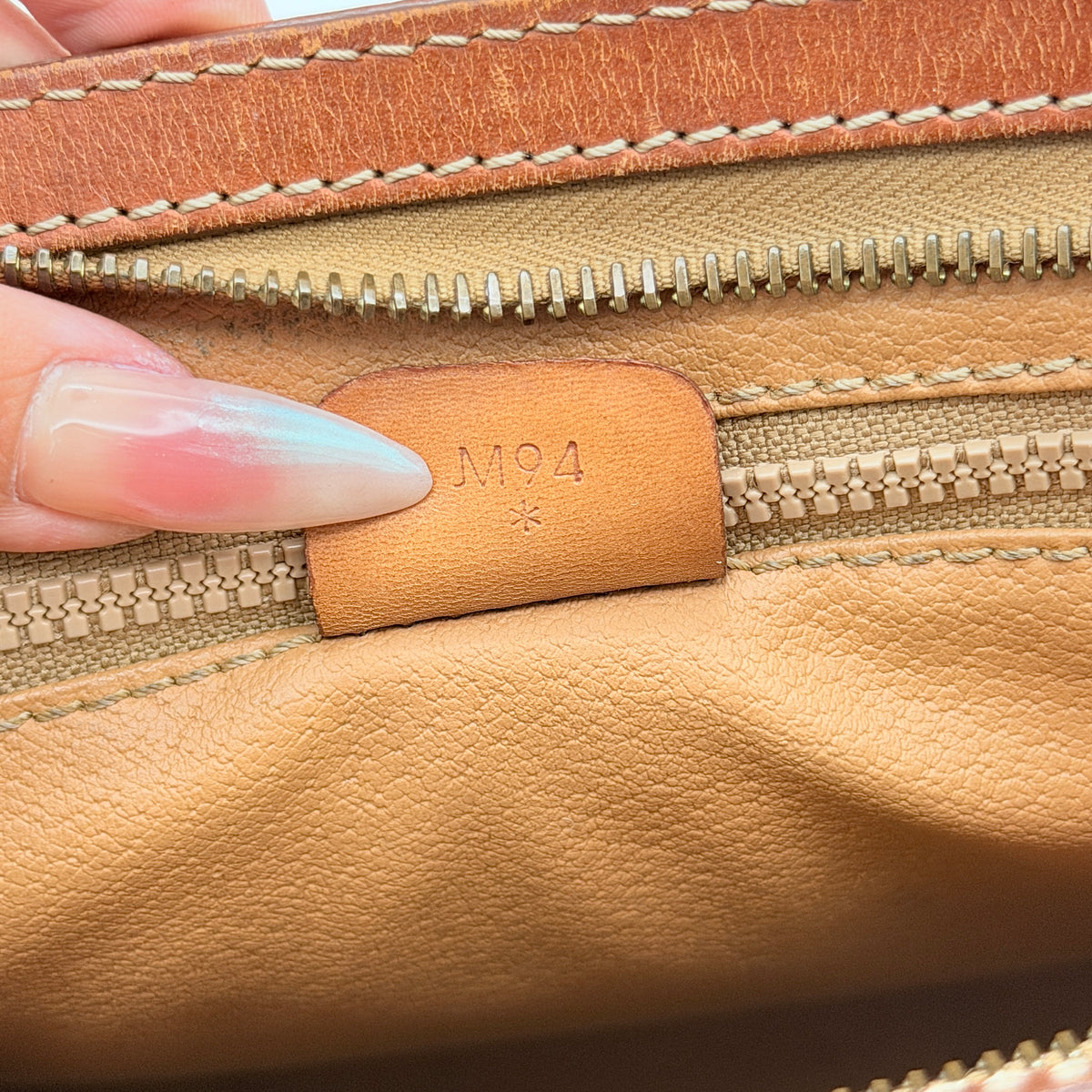 Celine Triomphe Macadam clutch bag in brown canvas with tan leather trim and gold hardware, shown with wrist strap.