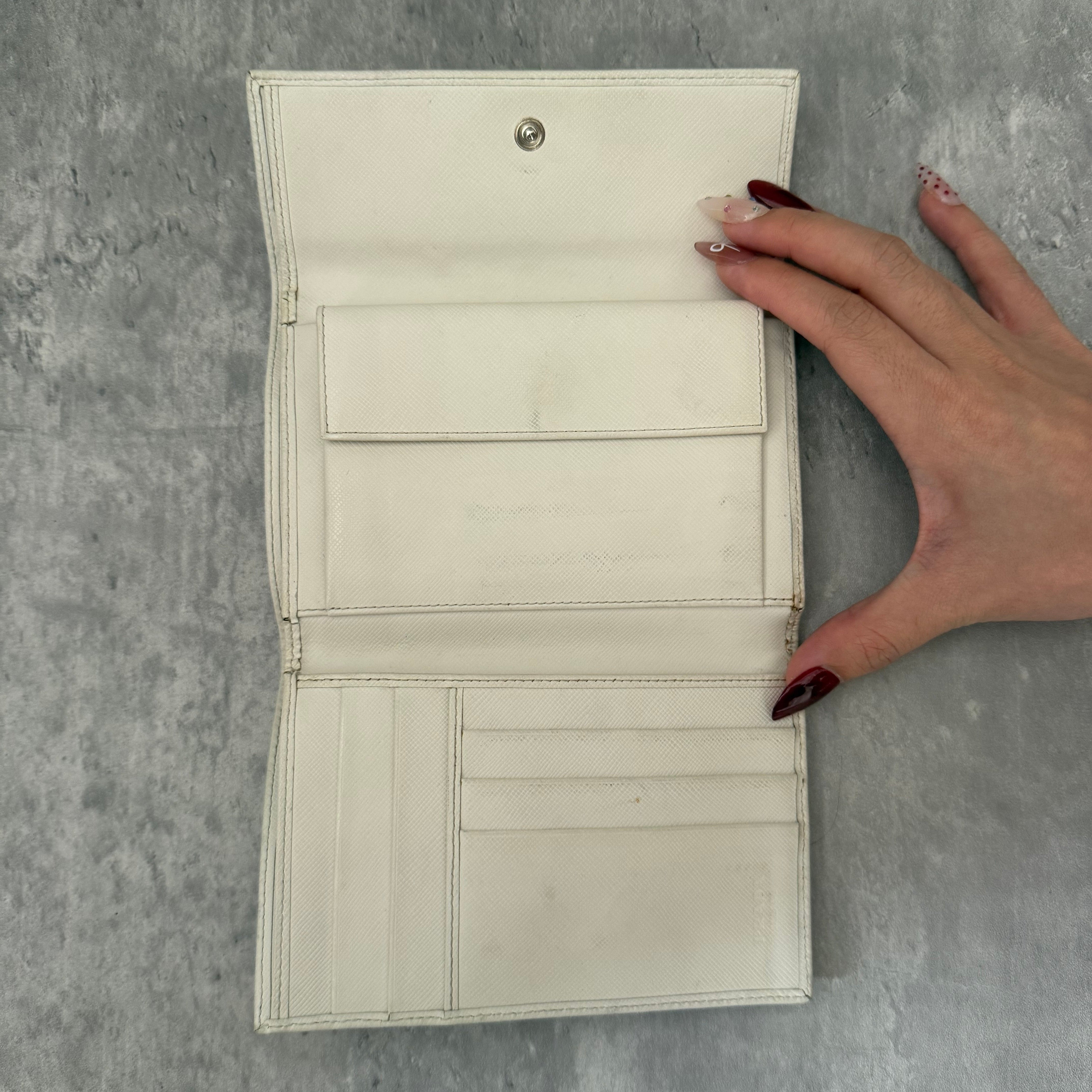 Pre-loved Prada Tessuto Nero leather trifold wallet with triangle logo plate in off-white, featuring card slots and a snap closure.