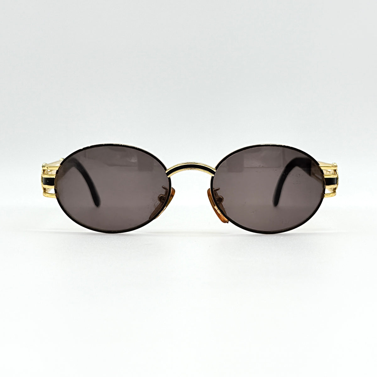 Fendi FF SL7031 oval sunglasses with gold-tone frame, brown lenses, and black arms, shown at an angled side view.