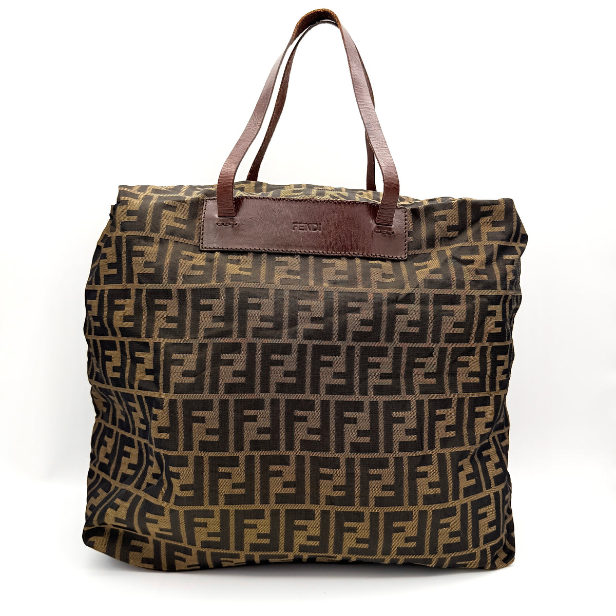Fendi FF Zucca foldable tote bag in brown canvas with leather top handles and all-over monogram, shown standing upright.