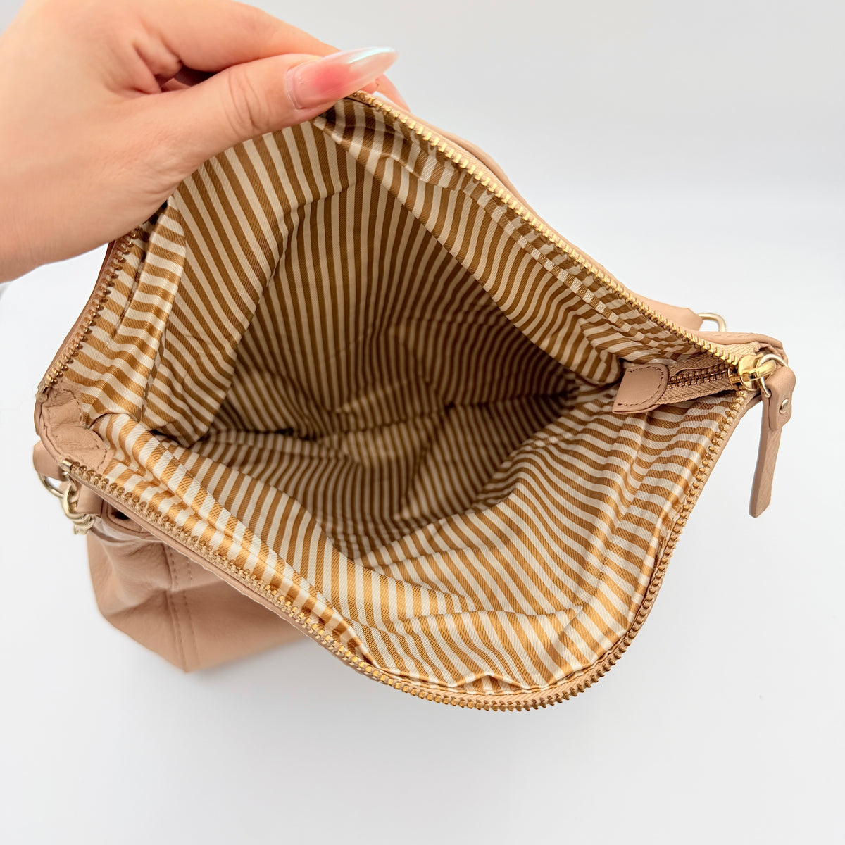 Kate Spade Cobble Hill Little Minka in beige pebbled leather with both top handle and detachable strap displayed.