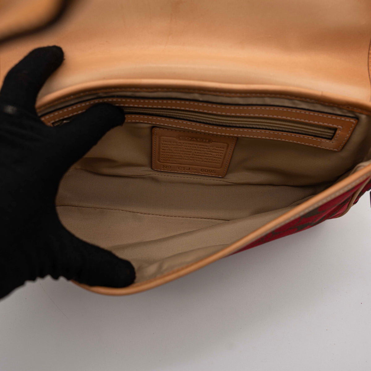 Coach Signature Soho Buckle Baguette in red and tan canvas with leather trim and a silver buckle, shown on a white background.