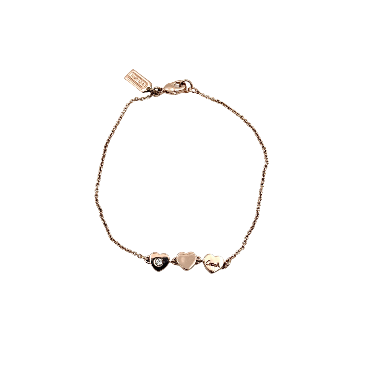 Coach gold bracelet featuring three heart-shaped charms, one with a crystal, one plain, and one engraved with the Coach logo.