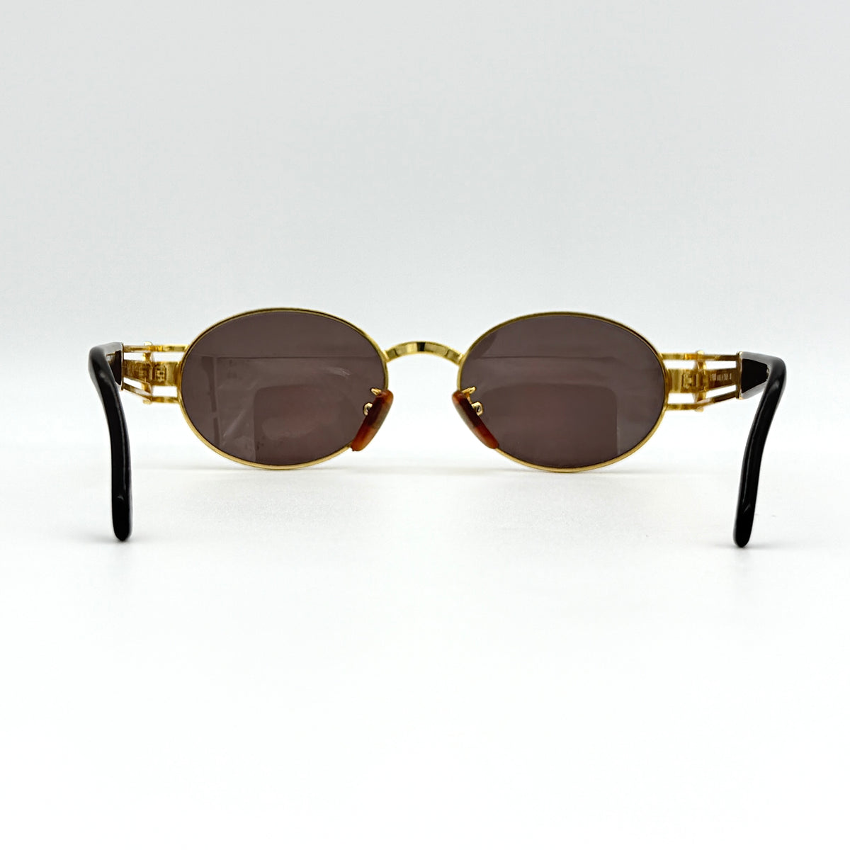 Fendi FF SL7031 oval sunglasses with gold-tone frame, brown lenses, and black arms, shown at an angled side view.