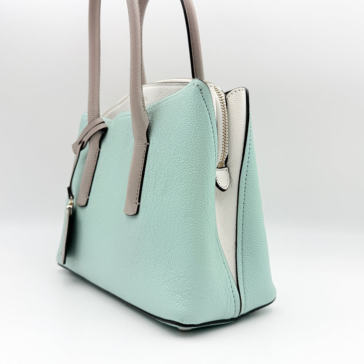 Kate Spade New York Margaux satchel in mint green pebbled leather with taupe handles, shown with its detachable strap and a clear pouch.