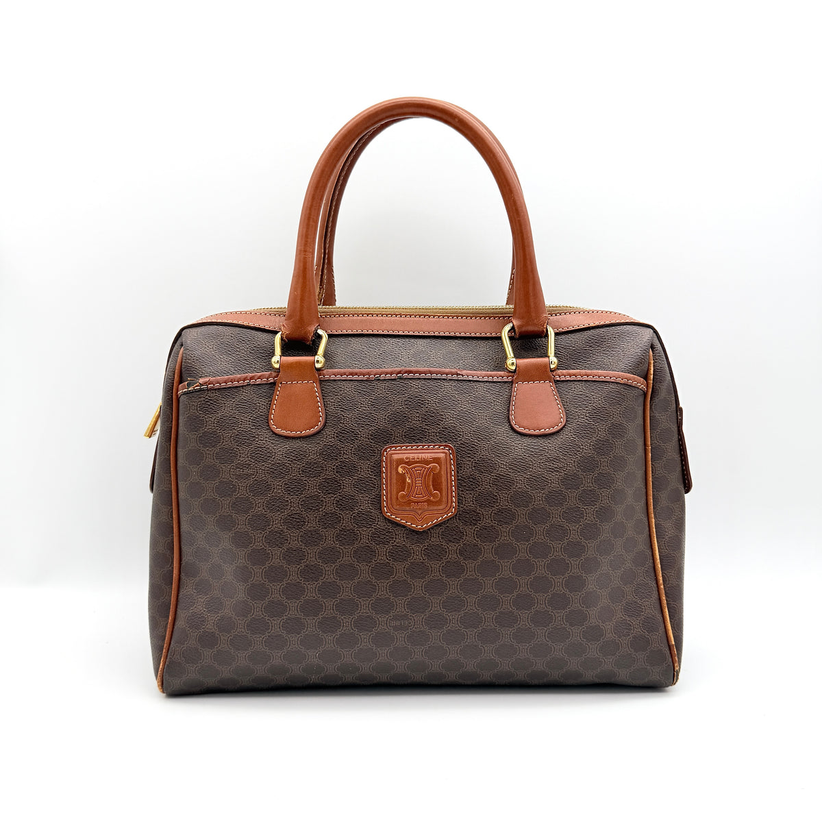 Celine Triomphe Macadam Boston Bag in brown coated canvas with tan leather handles and gold hardware on a white background.