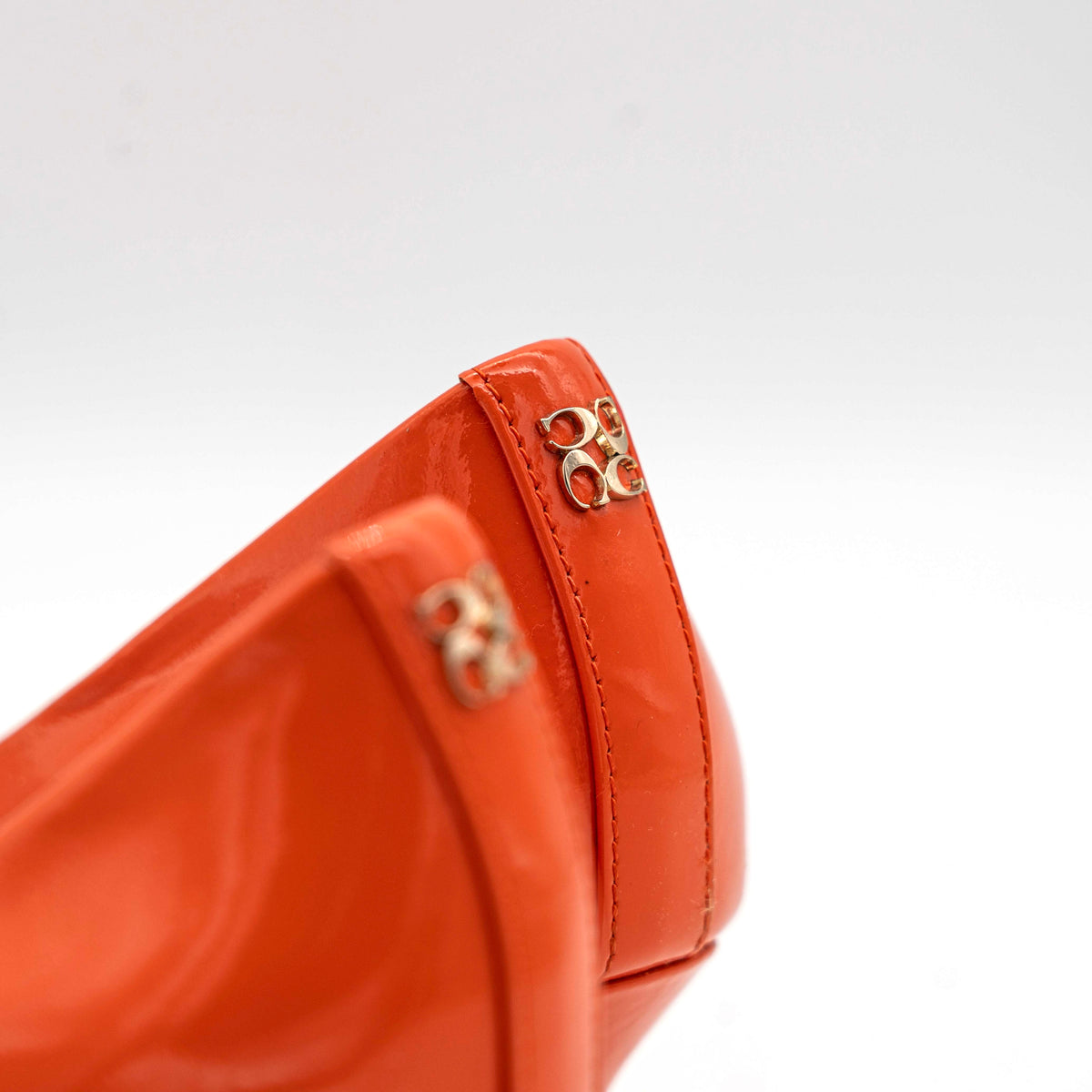 Pair of Coach orange patent leather pointed-toe heels with gold logo detail, size EU 35.5.
