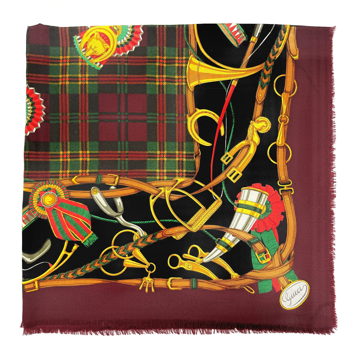 Gucci equestrian tartan shawl scarf in burgundy with heritage motifs and a fringed edge, styled folded.
