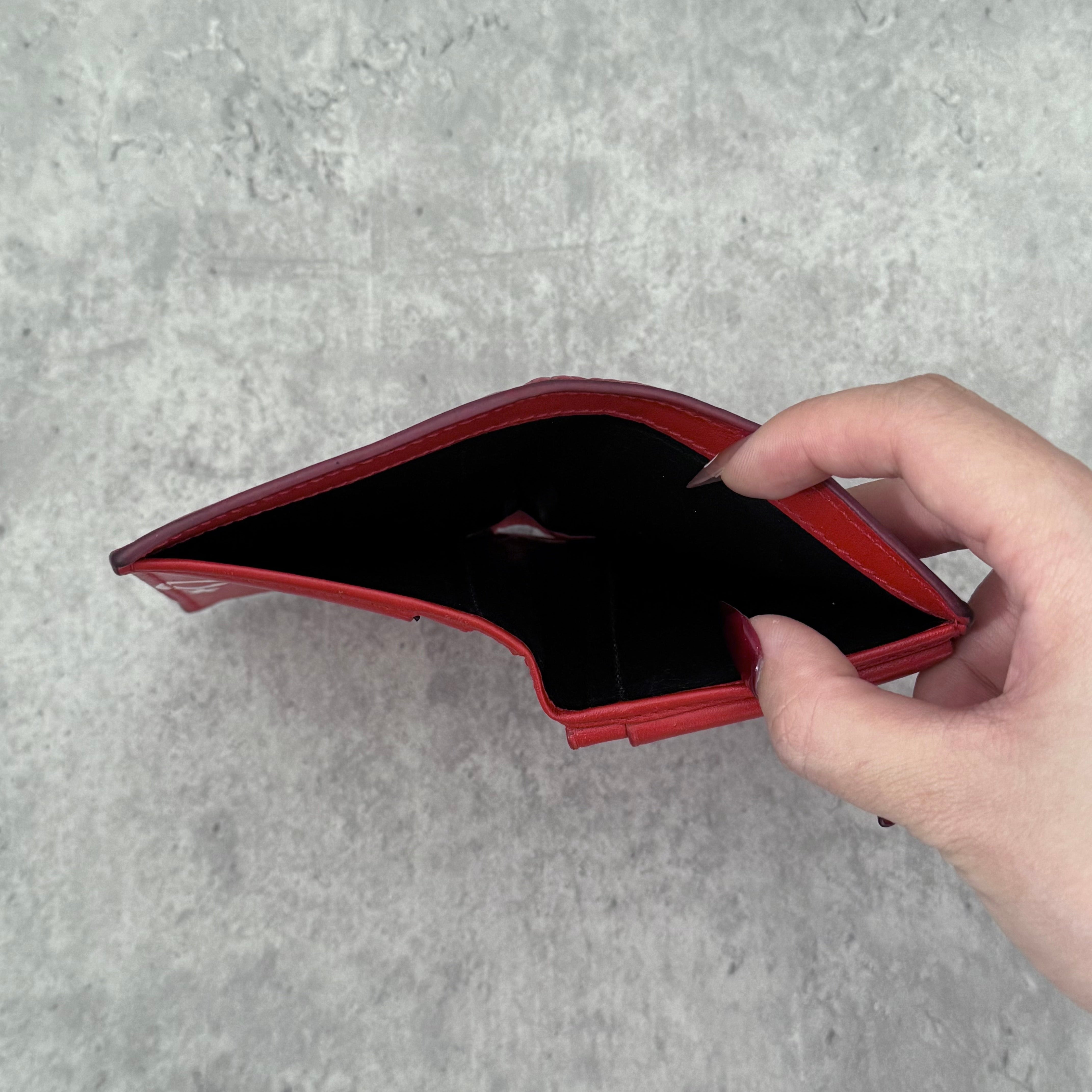 COMME des GARÇONS Huge Logo Red Leather Wallet with oversized white print and multiple card slots in a bi-fold design.