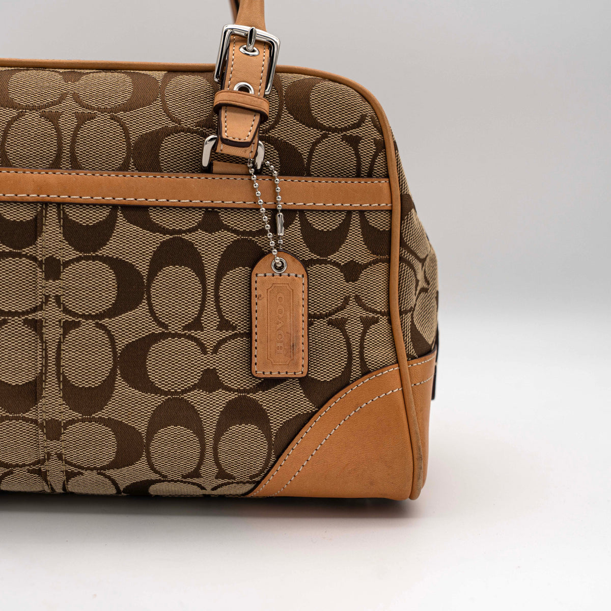 Coach Signature Hampton Satchel Boston Bag in beige and tan canvas with leather trim and silver hardware, styled on a clean background.