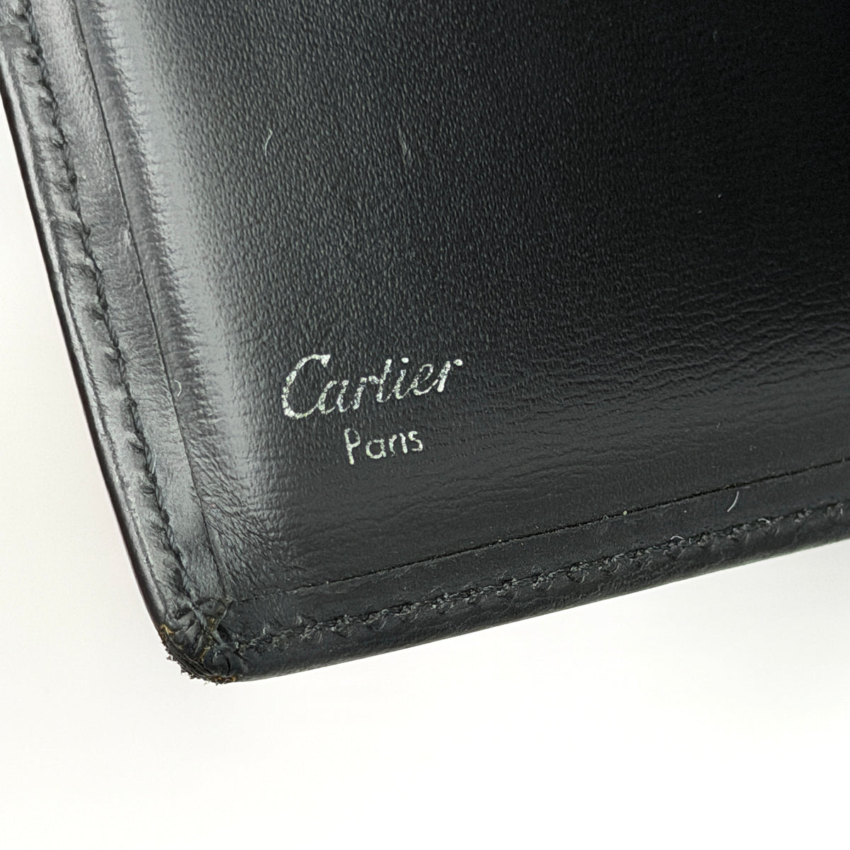 Cartier Must de Cartier black leather bifold wallet, shown with its signature red box and authentication card.
