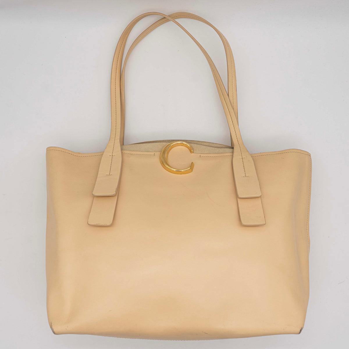 Chloé C Zipped Tote Bag in beige leather with gold hardware, shown with structured dual straps and front logo detail.