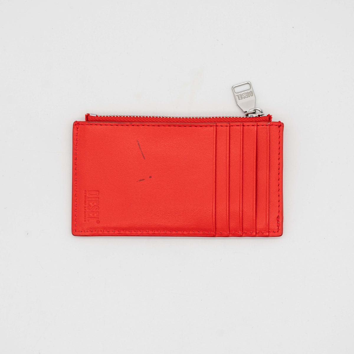 Diesel red patent card holder with silver logo plaque and top zip, set against a clean background.