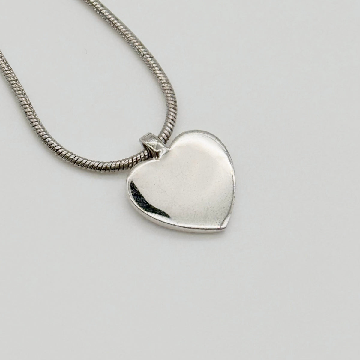Dior silver necklace with a rhinestone heart pendant and Dior logo, laid flat with CD tag visible.