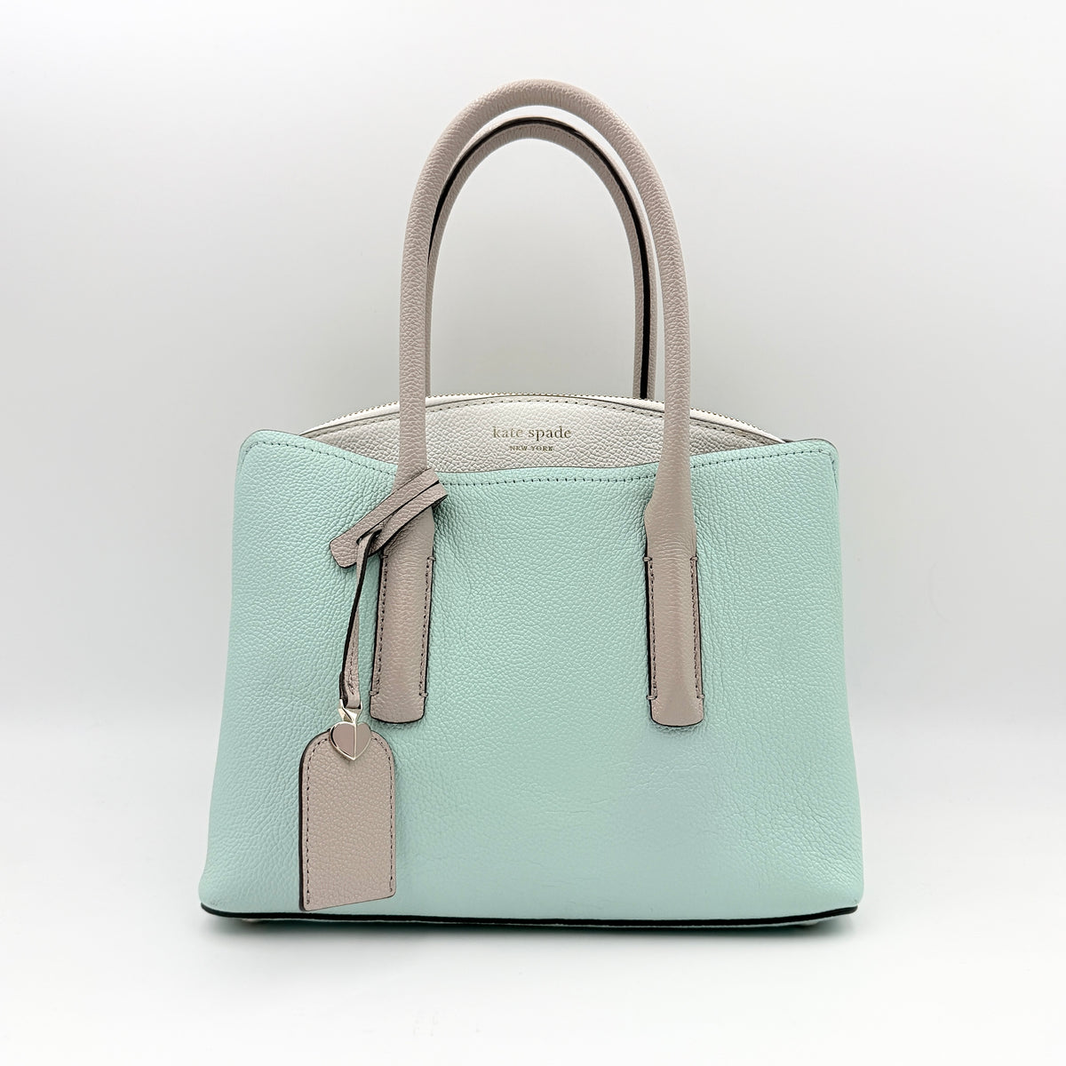 Kate Spade New York Margaux satchel in mint green pebbled leather with taupe handles, shown with its detachable strap and a clear pouch.