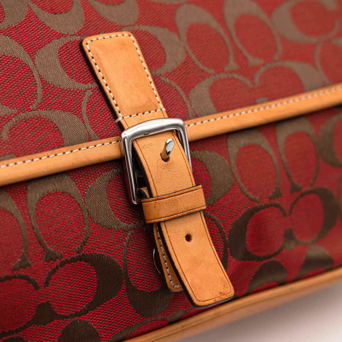Coach Signature Soho Buckle Baguette in red and tan canvas with leather trim and a silver buckle, shown on a white background.
