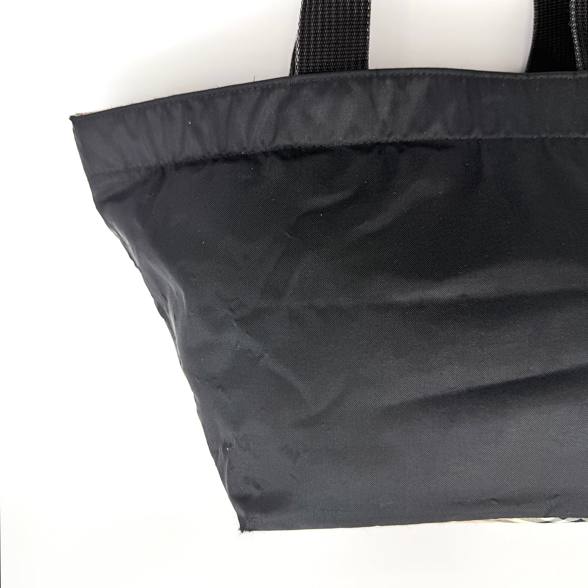 Burberry Blue Label Nova Check tote bag in black nylon with beige checked base and webbed handles, shown on white background.
