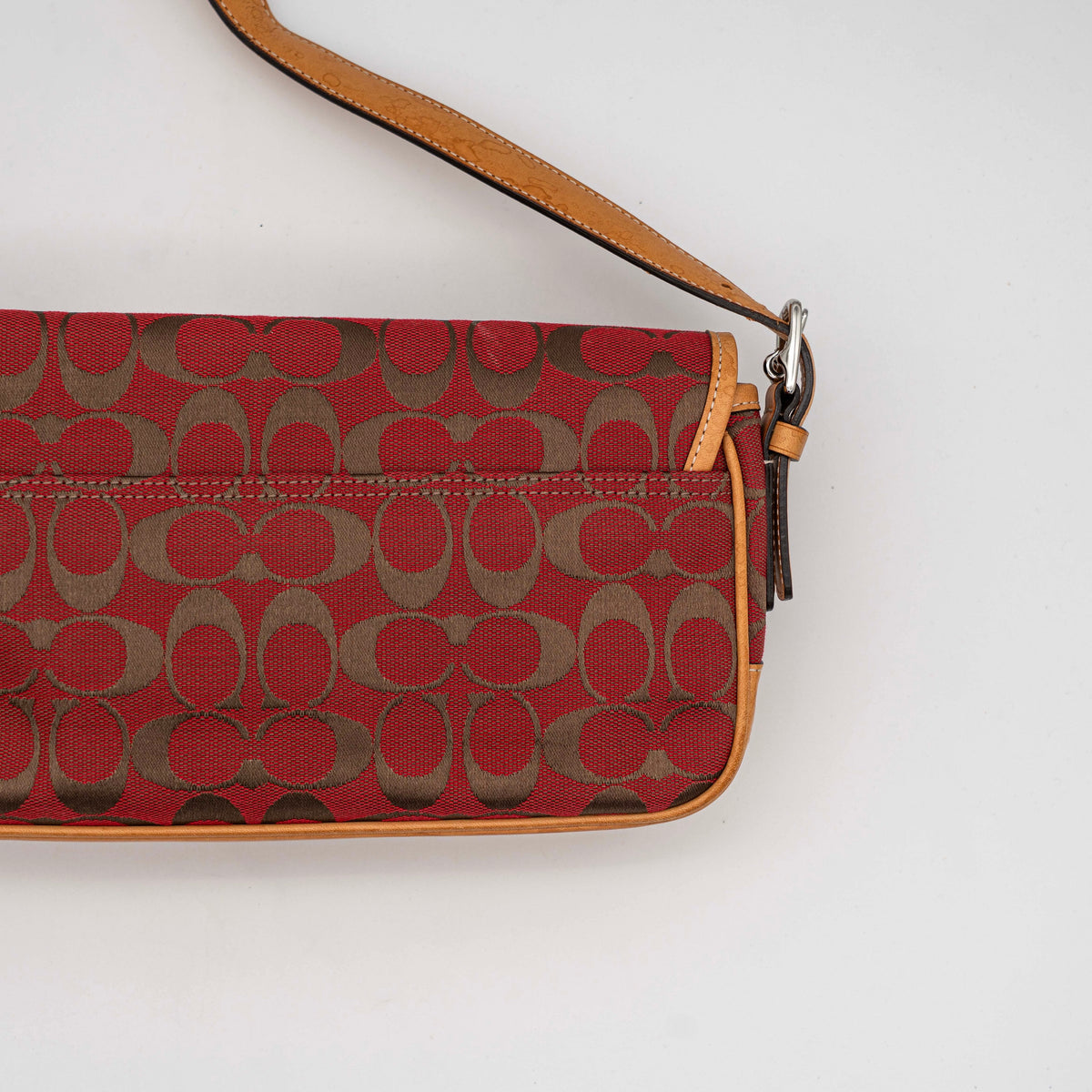 Coach Signature Soho Buckle Baguette in red and tan canvas with leather trim and a silver buckle, shown on a white background.