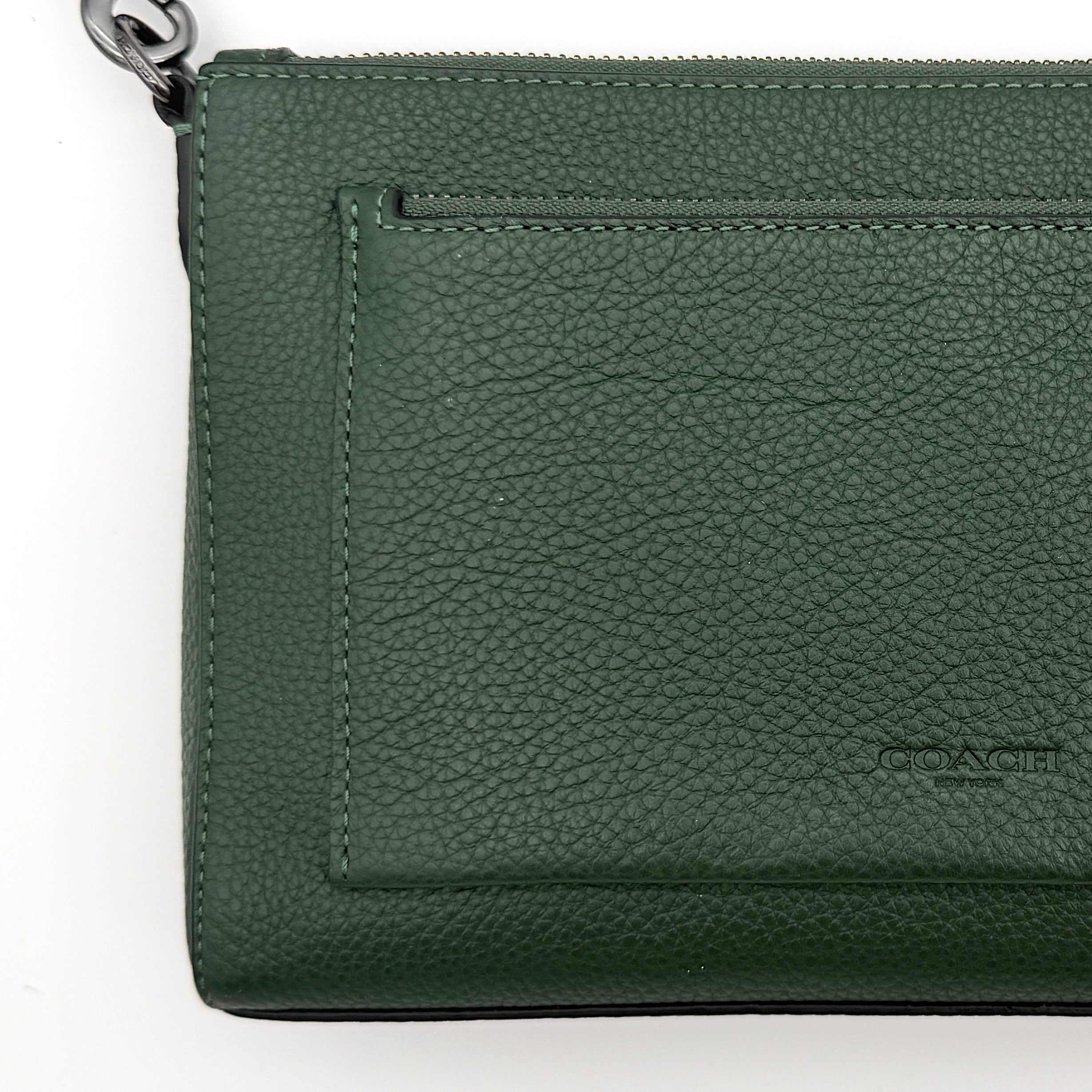 Coach Holden Crossbody bag in dark green pebbled leather with adjustable black webbing strap, displayed against a white background.