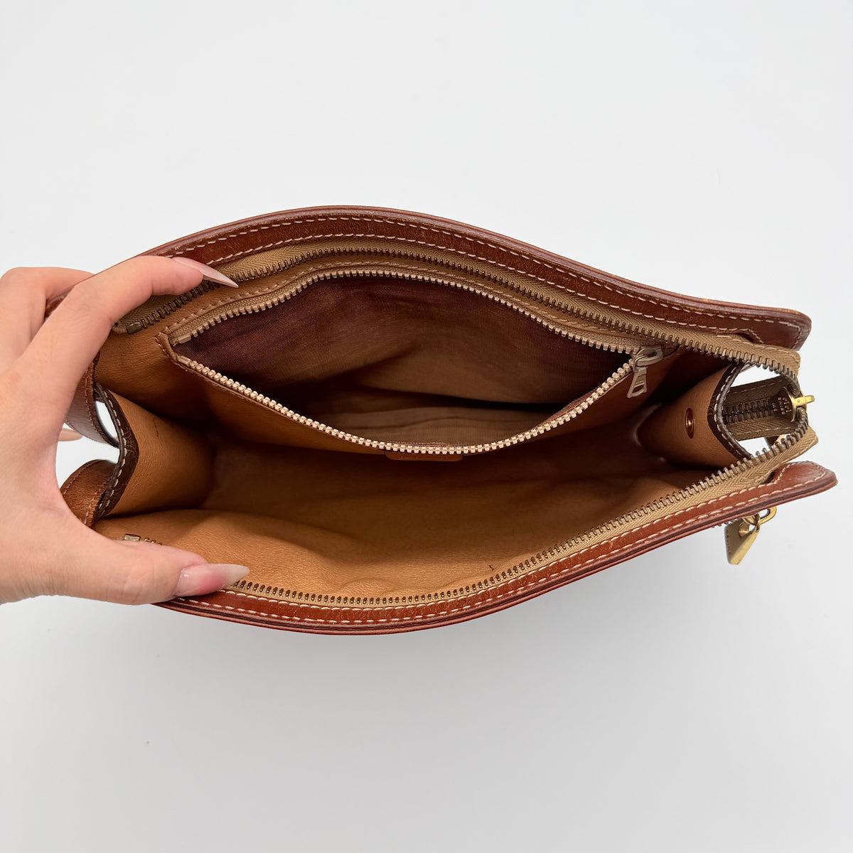 Celine Triomphe Macadam clutch bag in brown canvas with tan leather trim and gold hardware, shown with wrist strap.