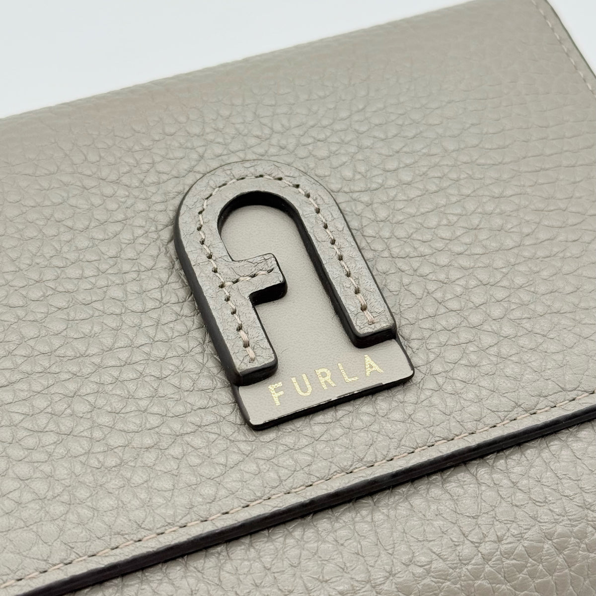 Furla Dafne Trifold Wallet in grey pebbled leather with gold-tone hardware and trifold interior, shown with original dust bag.