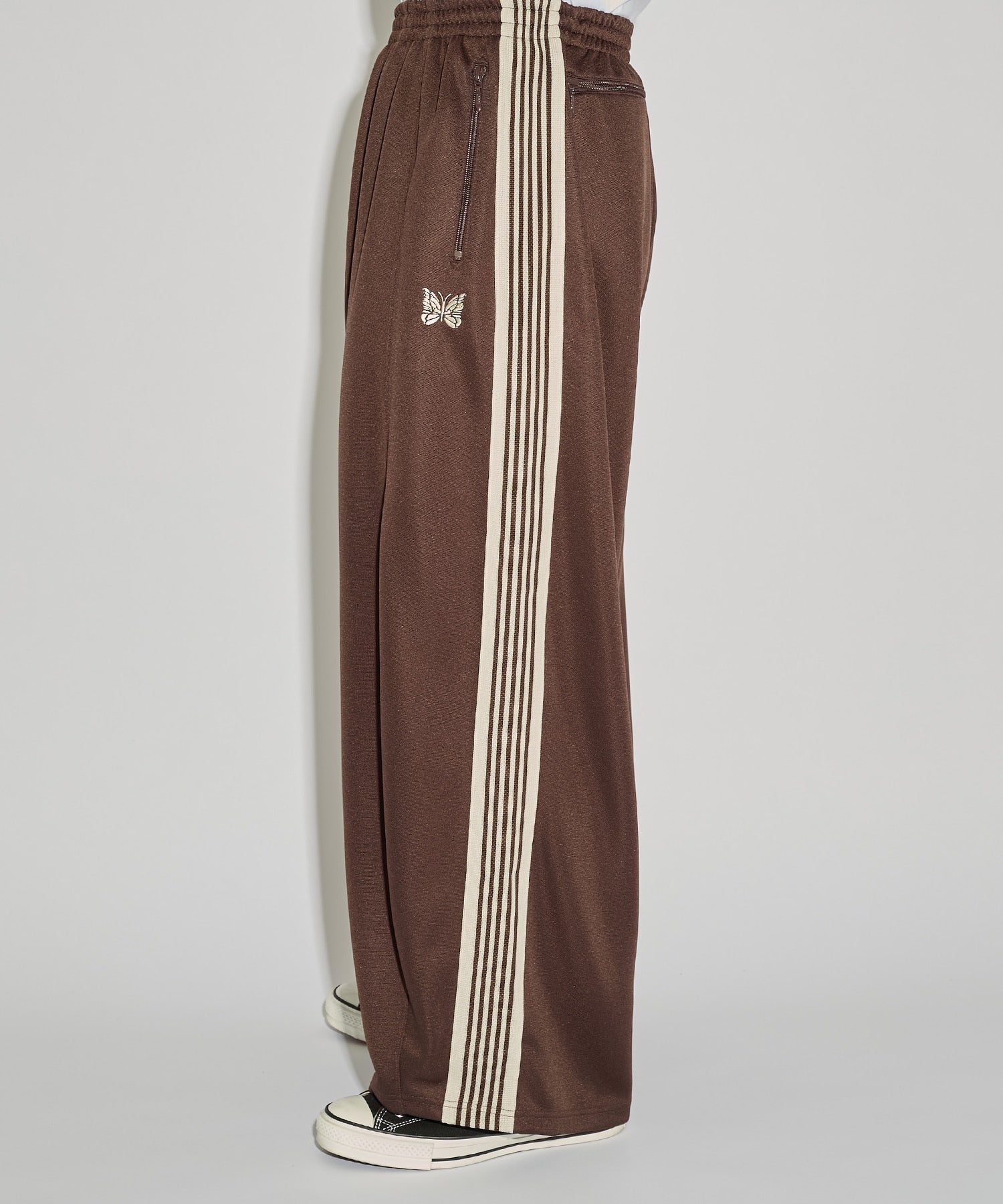 Needles H.D. Track Pant in brown with cream stripes and butterfly embroidery, shown in a side view that highlights the wide leg fit.