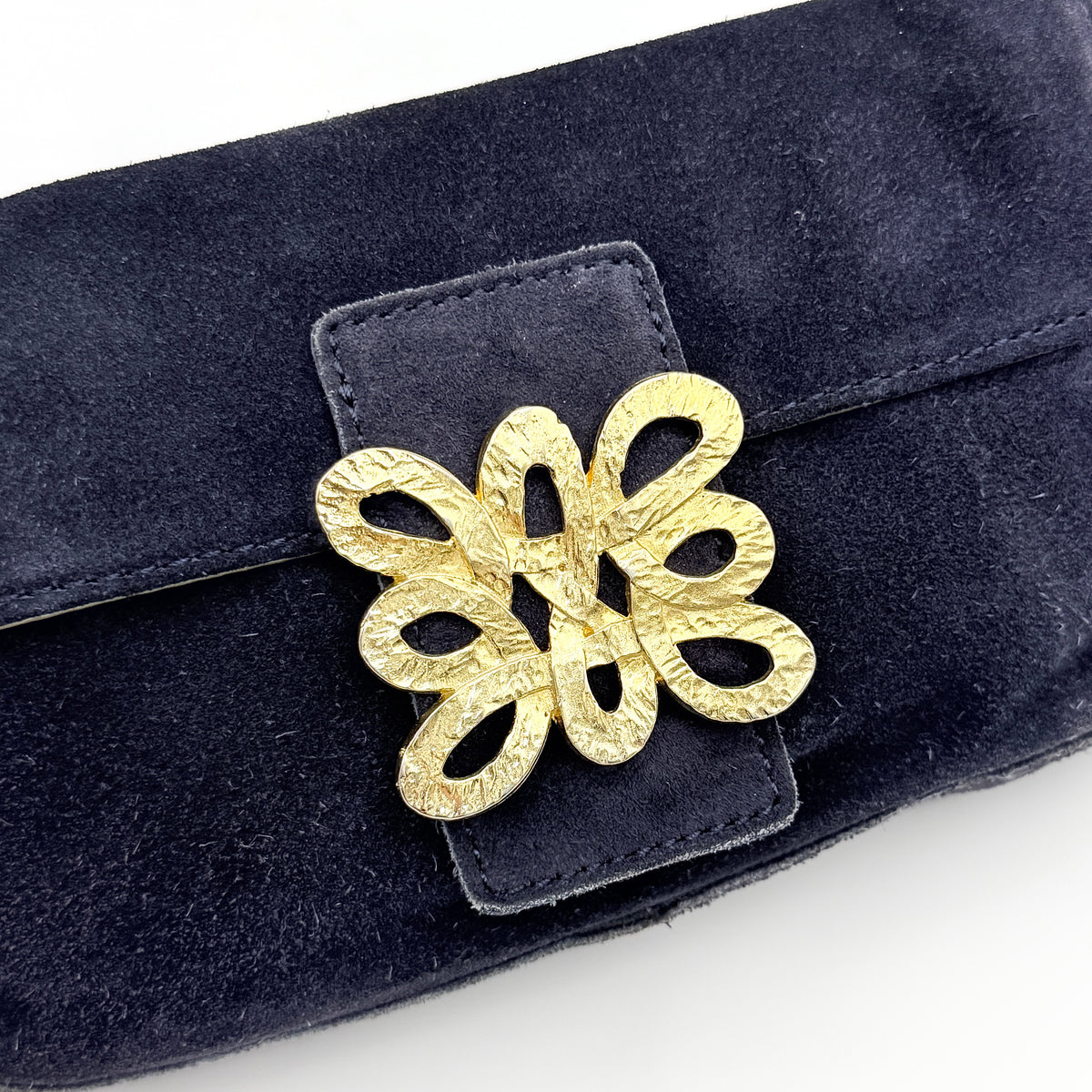Navy blue suede Kate Spade baguette bag with floral gold hardware and gold-tone shoulder strap.