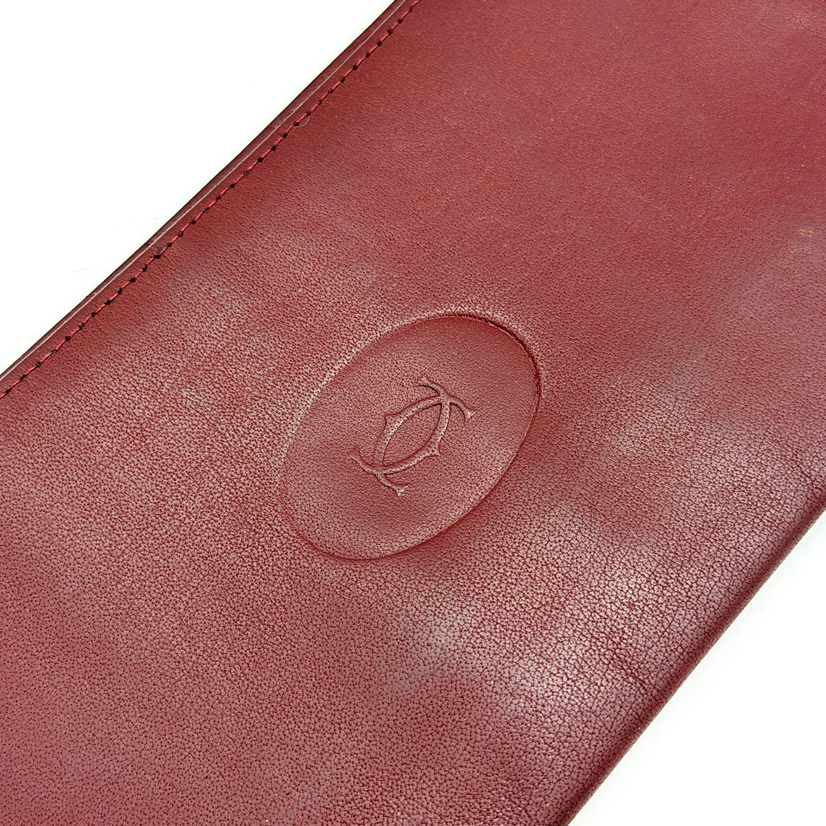 Cartier Must de Cartier burgundy leather bifold long wallet with embossed logo and organized interior compartments.