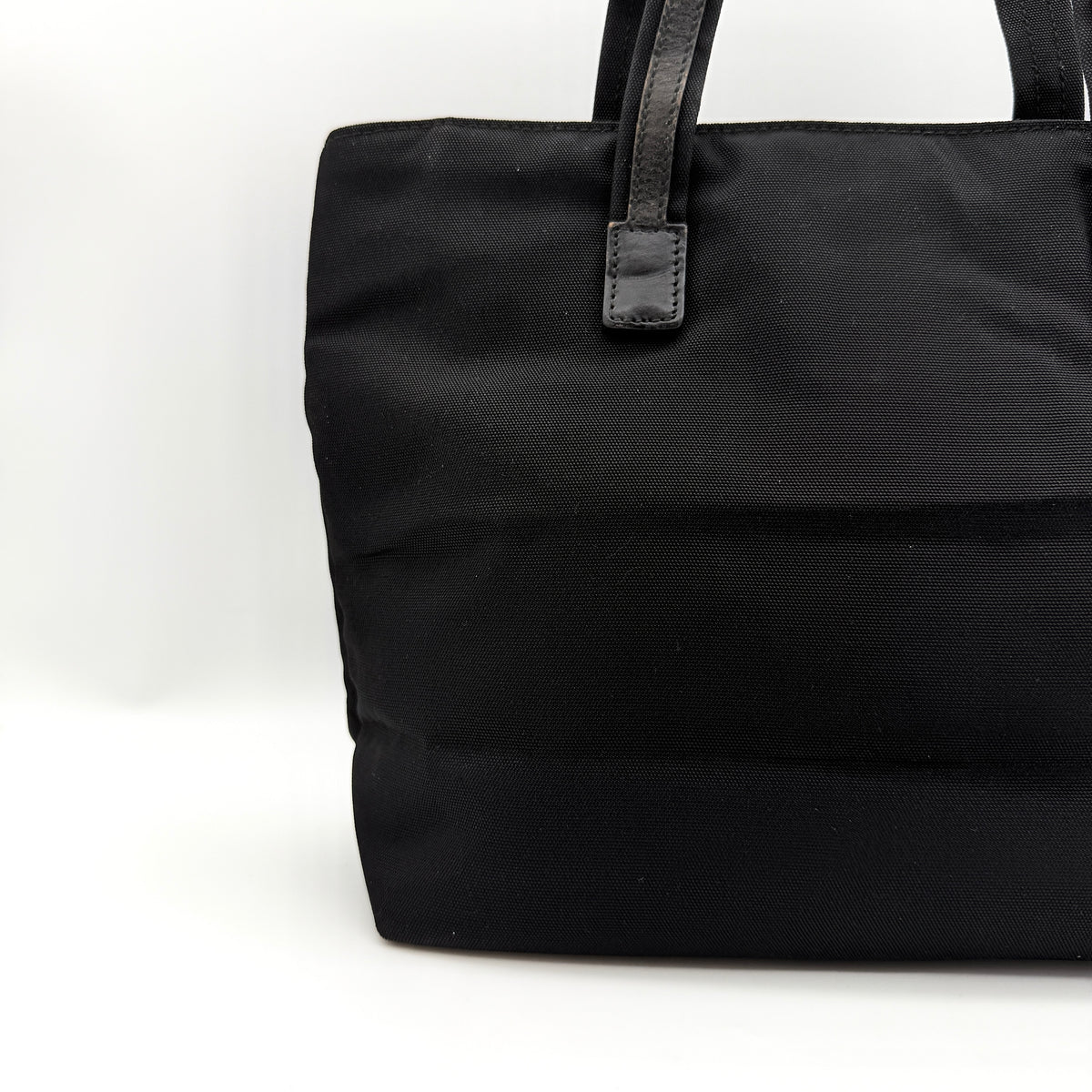 Front view of the Gucci black nylon tote with dual zip pockets and leather top handles.
