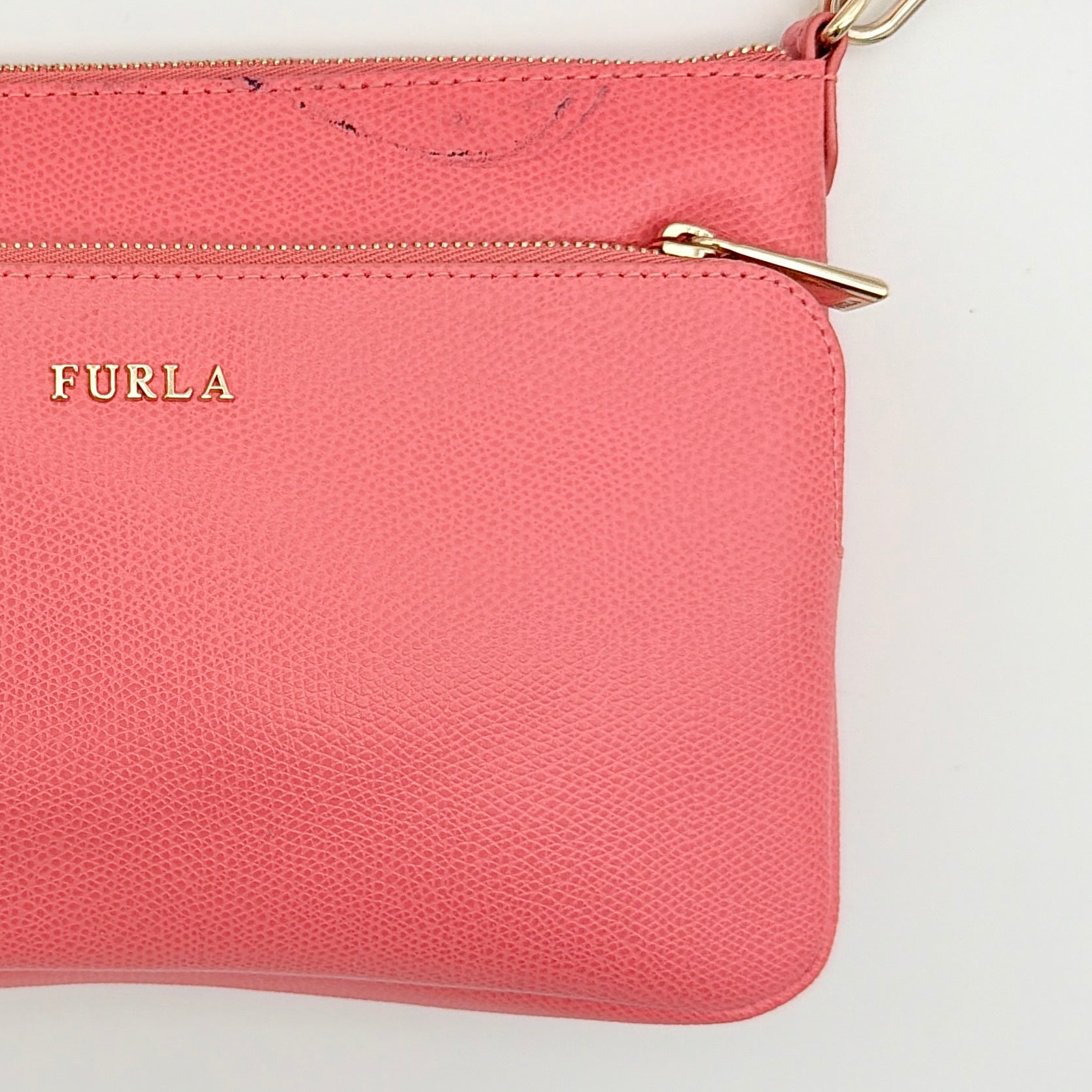Furla pink leather crossbody bag with gold zip and adjustable strap, photographed flat on a white background.