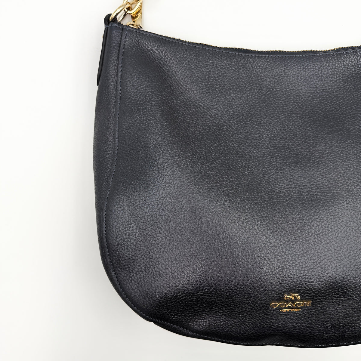 Coach Elle Hobo bag in navy blue pebbled leather with gold hardware and a detachable strap, styled on a white background.