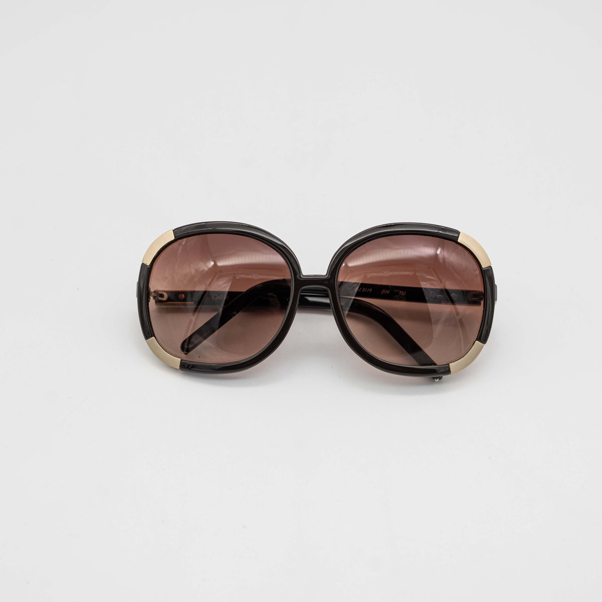 Chloé CL2119 sunglasses in black with gold-tone accents and brown gradient lenses, displayed at an angle.
