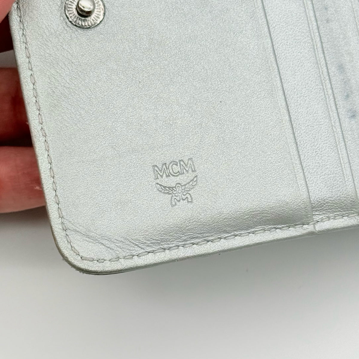MCM Visetos Monogram wallet in metallic silver with black logo pattern on a clean white background.
