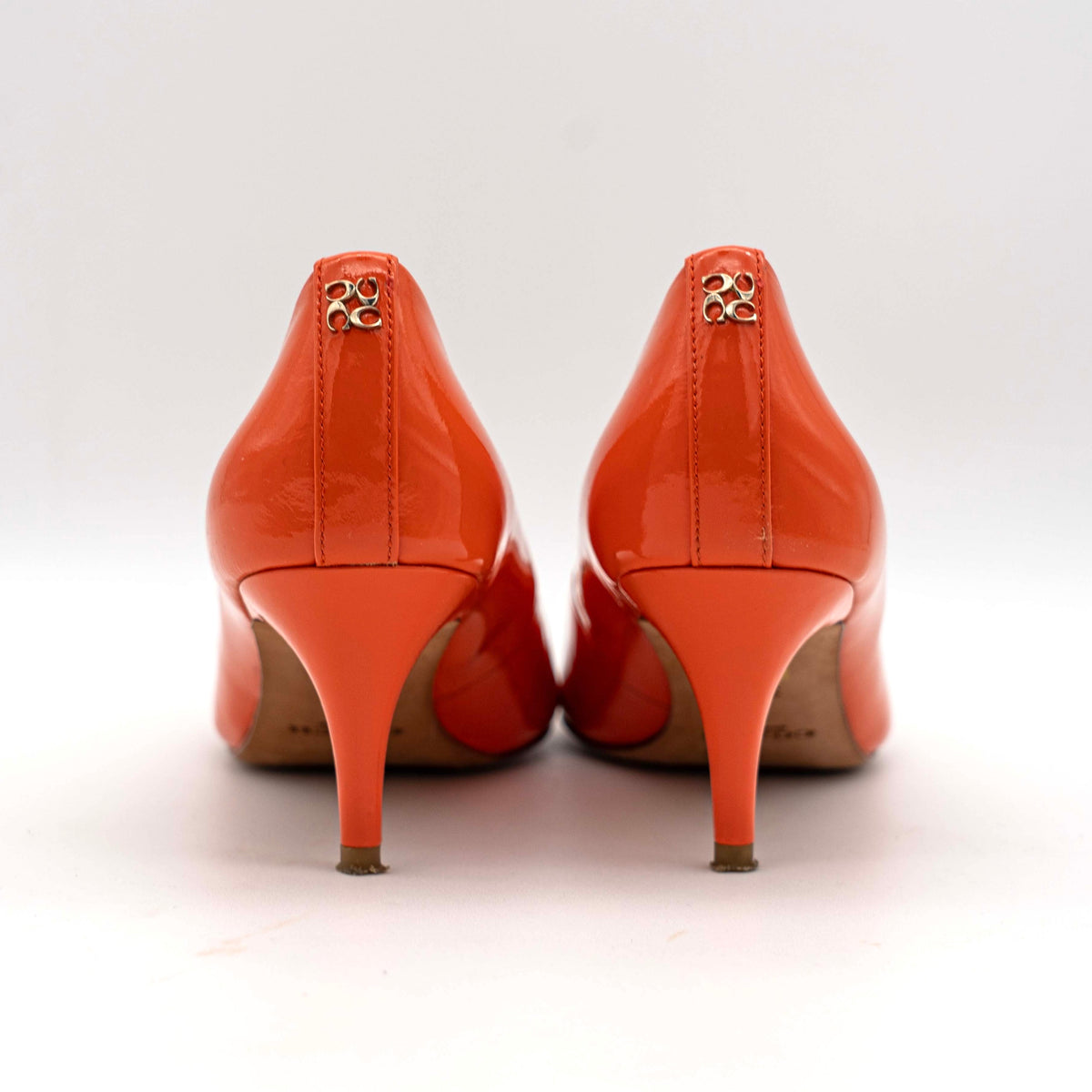Pair of Coach orange patent leather pointed-toe heels with gold logo detail, size EU 35.5.
