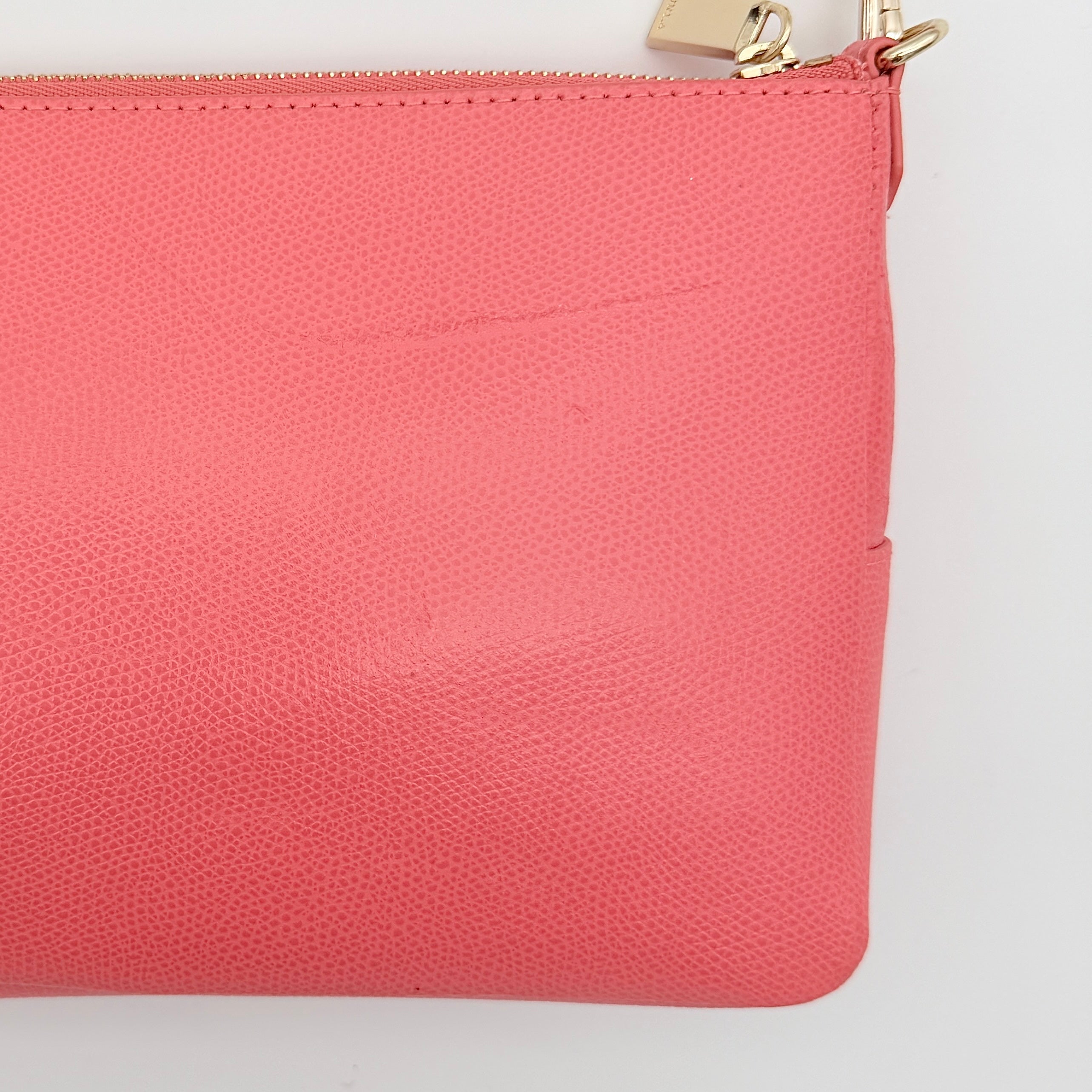 Furla pink leather crossbody bag with gold zip and adjustable strap, photographed flat on a white background.